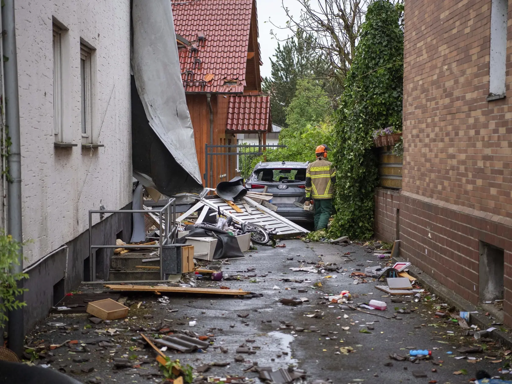 Hasič kráča okolo zničeného auta po pravdepodobnom vyčíňaní tornáda v nemeckom Lippstadte.