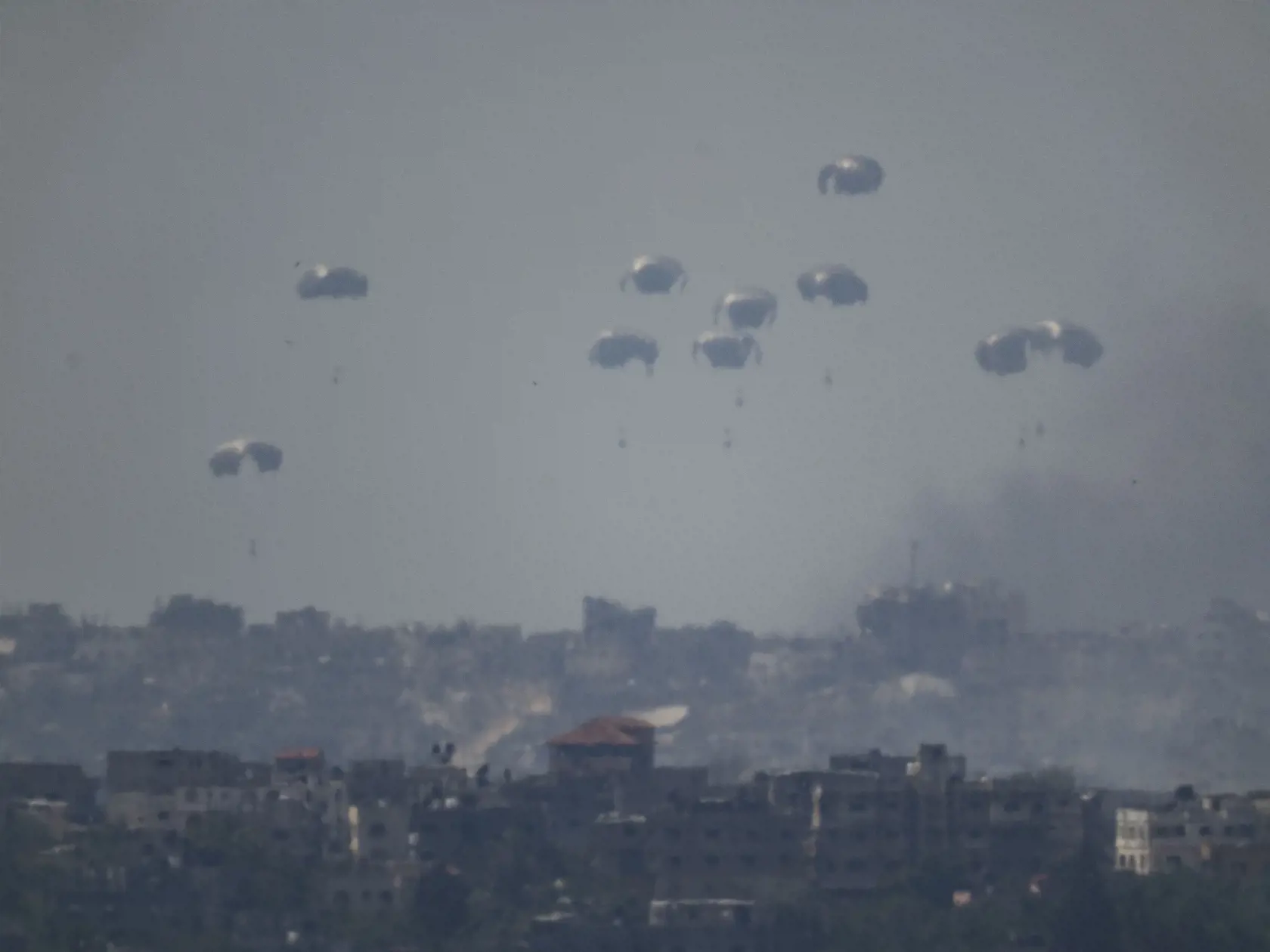 Padáky s humanitárnou pomocou sú zhadzované nad severom pásma Gazy, čo je viditeľné z juhu Izraela v utorok 9. apríla 2024. Izraelská armáda bojuje s palestínskymi militantmi hnutia Hamas v pásme Gazy po útokoch Hamasu na Izrael 8. októbra.