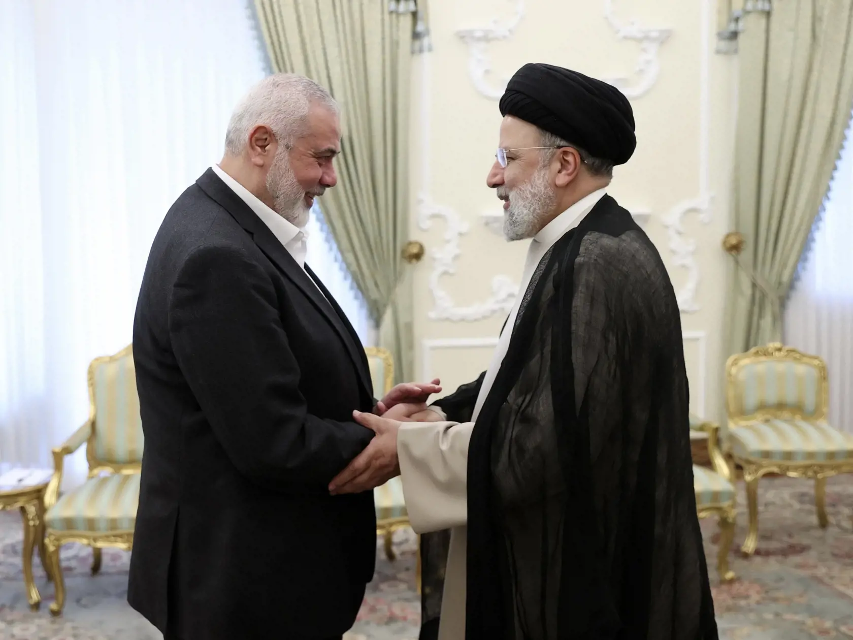 Iránsky prezident Ebráhím Raísí (vpravo) si podáva ruku s vodcom palestínskeho radikálneho hnutia Hamas Ismáílom Haníjom pred ich stretnutím v Teheráne 27. marca 2024.