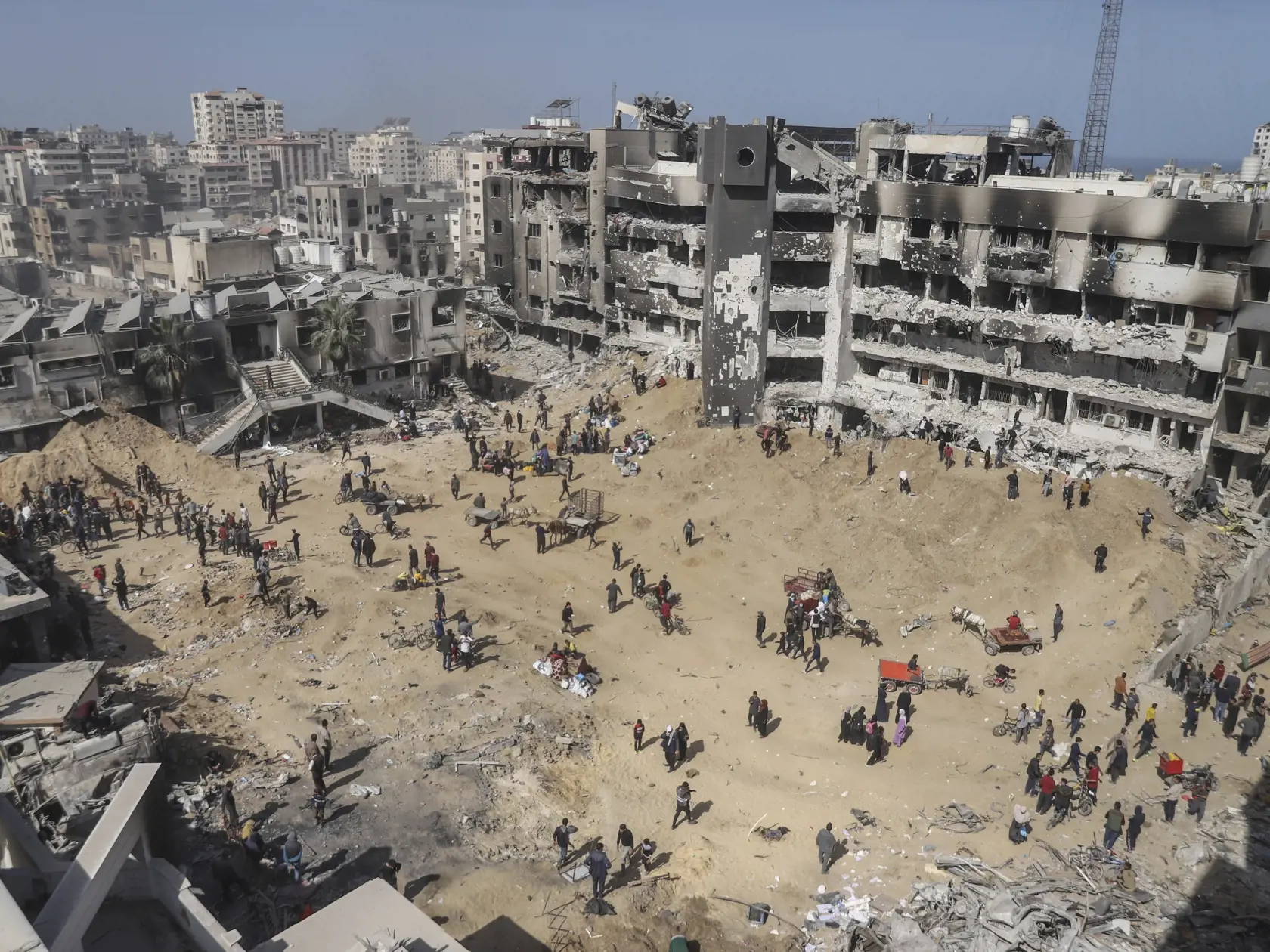 Palestínčania kráčajú po zničenom území, ktoré zanechala izraelská letecká a pozemná ofenzíva neďaleko nemocnice Šifa v meste Gaza v Pásme Gazy v pondelok 1. apríla 2024.  Izraelská armáda v pondelok potvrdila ukončenie svojej dvojtýždňovej operácie v okolí nemocnice a stiahnutie svojich vojakov. Nemocnica Šifá je  najväčšie zdravotnícke zariadenie v Pásme Gazy nachádzajúcom  sa v meste Gaza.