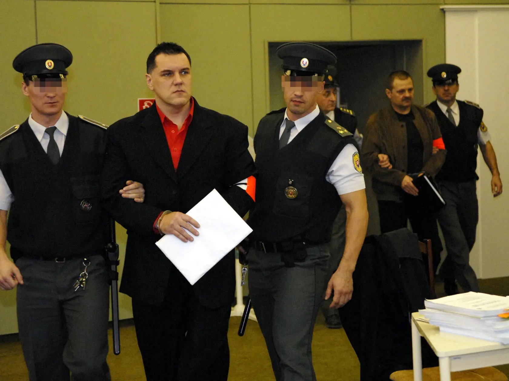 Mikuláš Černáka, za ním jeho bývalý švagor Jozef Matula na pojednávaní v prešovskej base počas procesu, v ktorom boli stíhaní za vraždu podnikateľa Mariána Karcela.