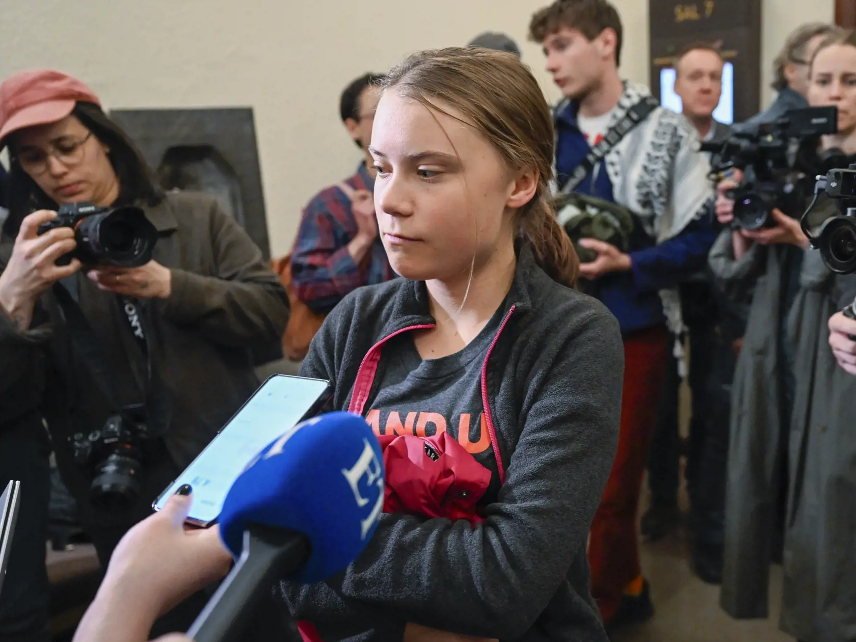 Švédska klimatická aktivistka Greta Thunbergová odpovedá na otázky novinárov v budove súdu v Štokholme 8. mája 2024.