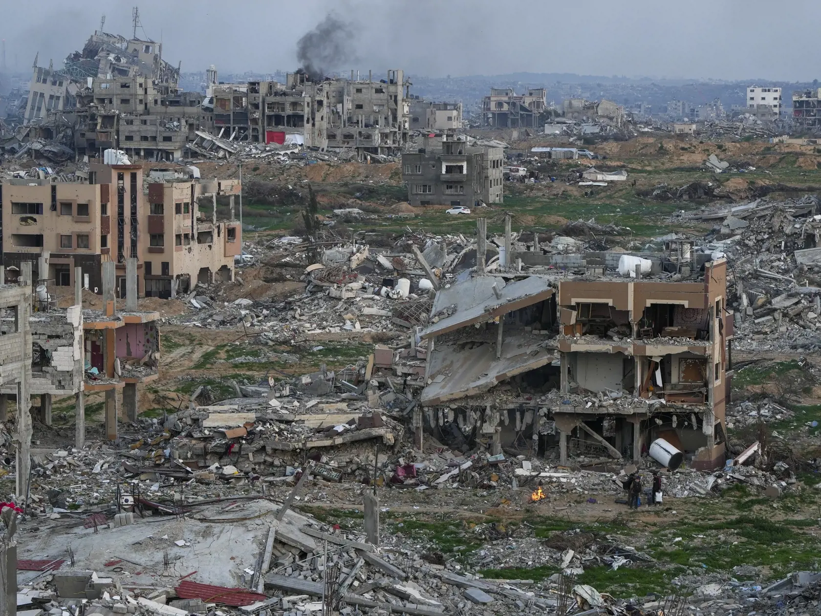 Ľudia stoja pri ohni medzi troskami zničených budov počas bojov medzi izraelskom armádou a palestínskym militantným hnutím Hamas v meste Gaza v utorok 4. februára 2025.