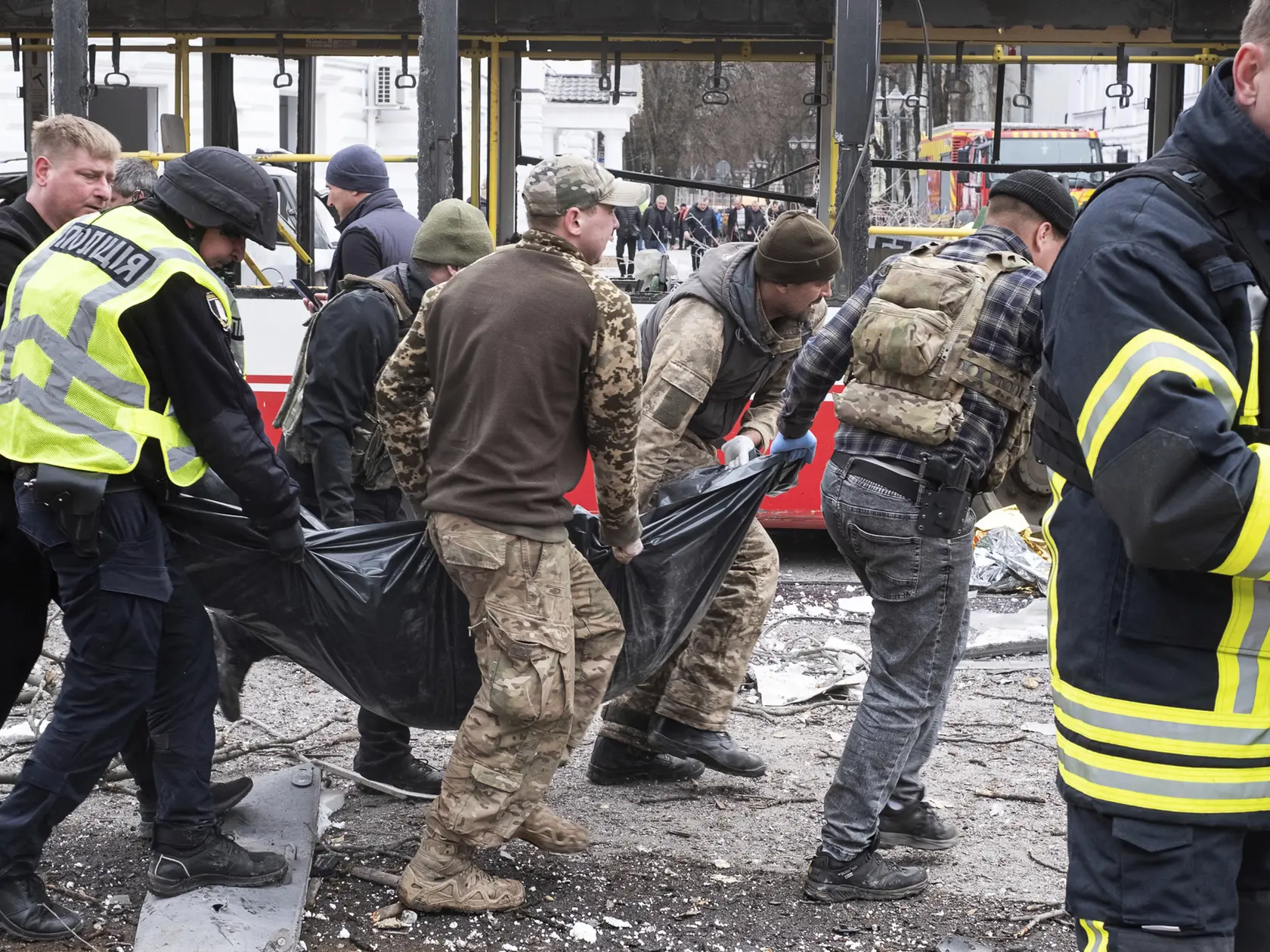 Policajní príslušníci nesú mŕtve telo po ruskom útoku.