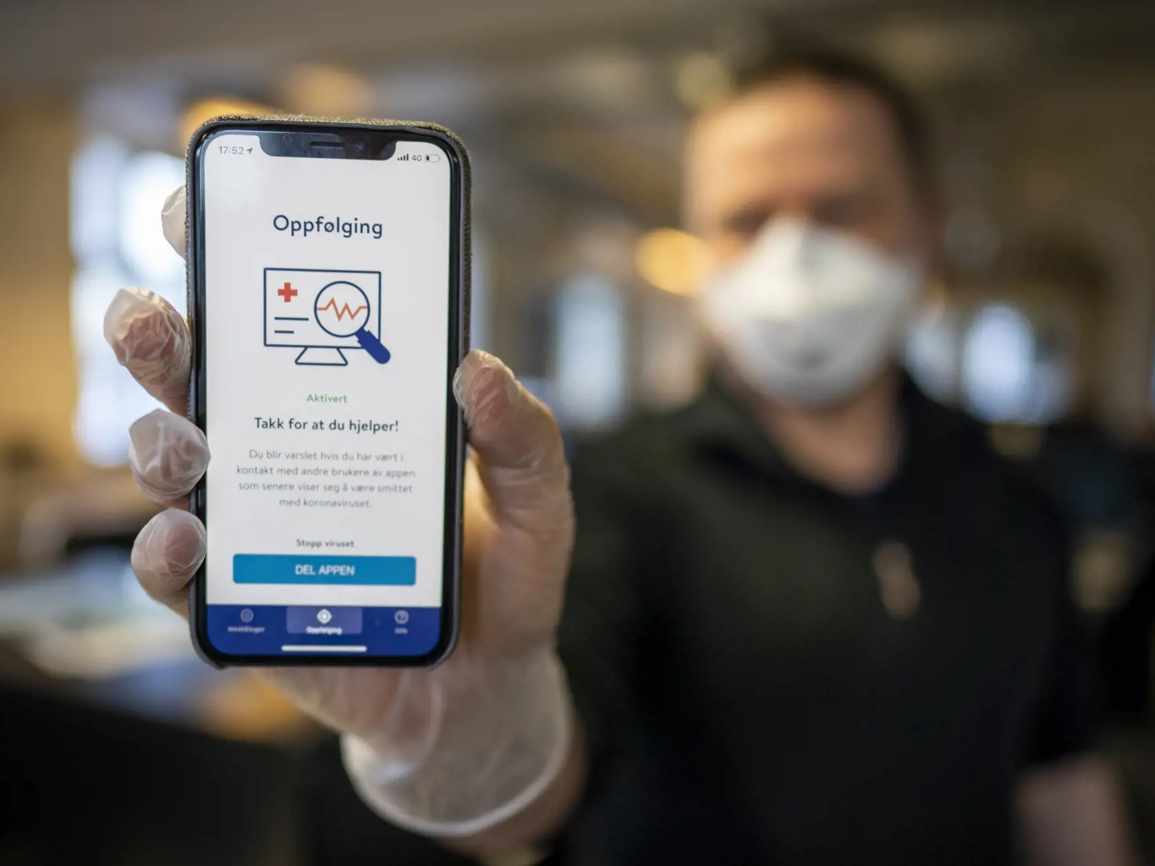 Muž ukazuje mobilný telefón s mobilnou aplikáciou na monitorovanie pohybu nakazených ľudí v Osle.