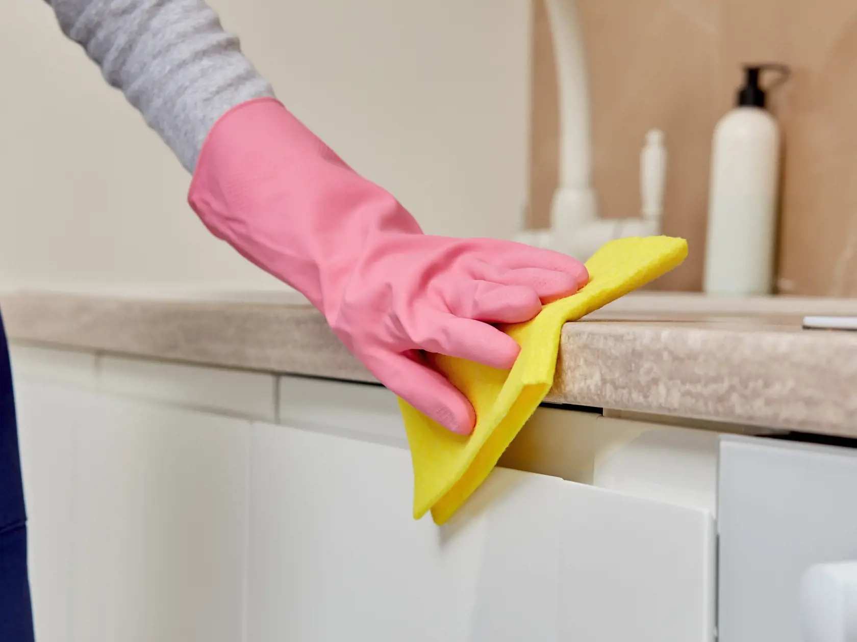 Close-up of a woman's hand in a rubber glove with microfiber. A woman is cleaning the kitchen. Without a face. Home routine. Professional cleaning.