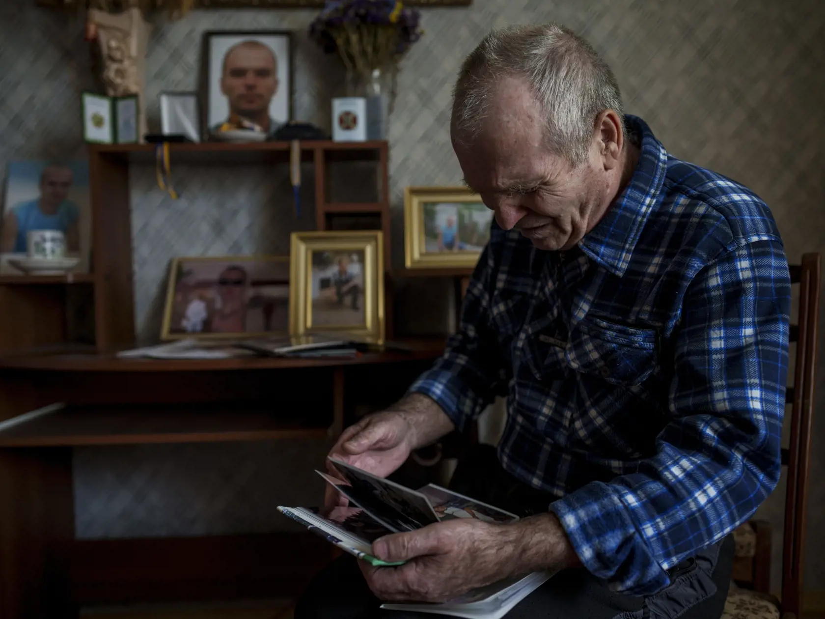 Oleksandr Turovskyj, ktorého 35-ročný syn Sviatoslav bol v marci 2022 medzi ôsmimi mužmi popravenými na prázdnom pozemku v ukrajinskom meste Buča v Kyjevskej oblasti, sa pozerá na fotografie syna vo svojom dome v Buči v sobotu 30. marca 2024.
