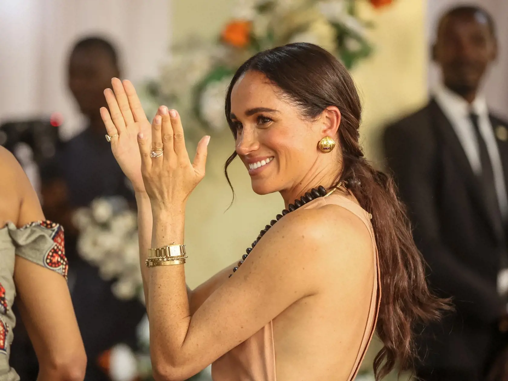 Meghan žiarila v broskyňových šatách s holým chrbtom.