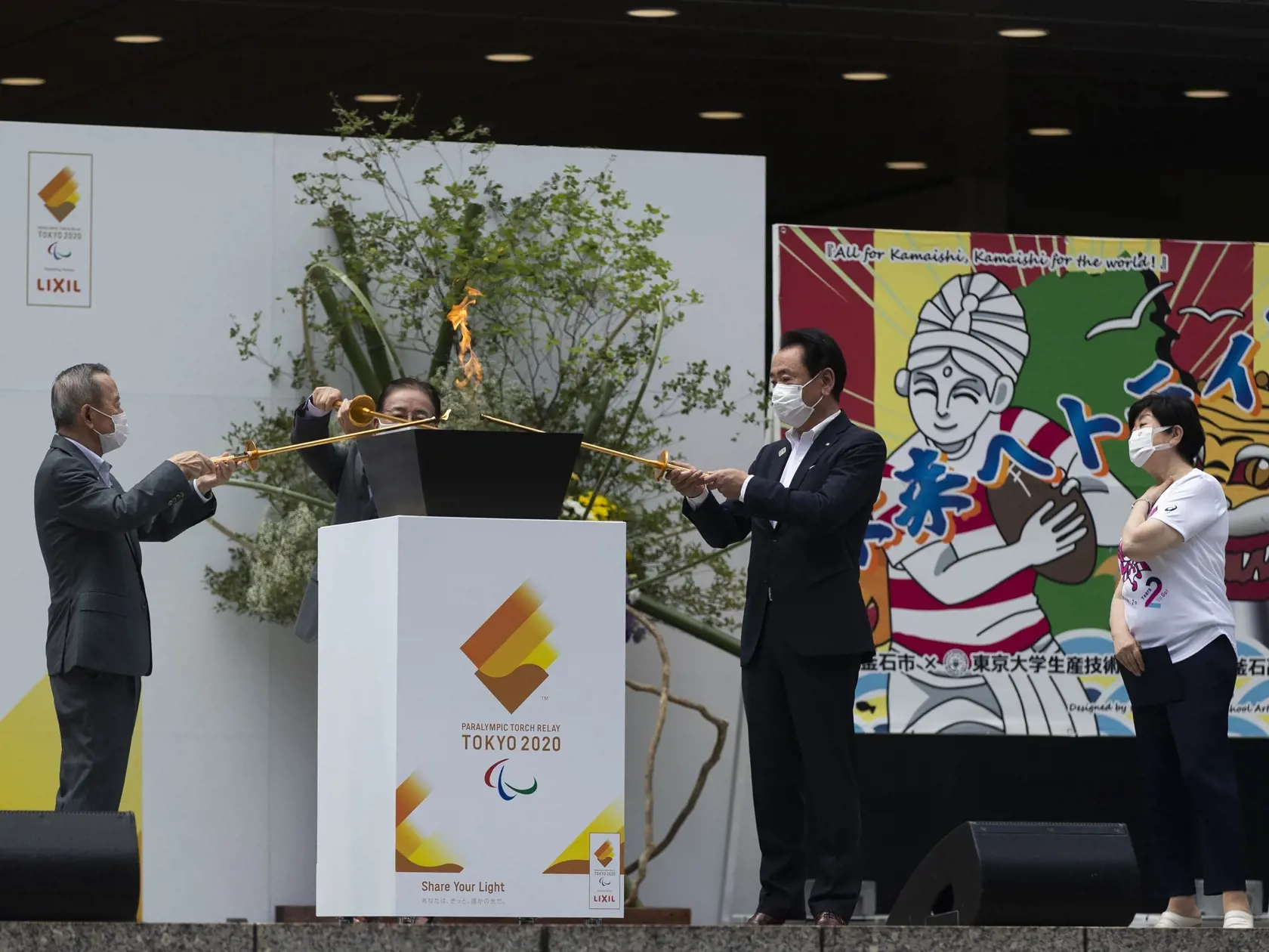 WA 36 Tokio - Starostka Tokia Juriko Koike (vpravo) sleduje trojicu mužov, ktorí zapaľujú paralympijský oheň v Tokiu v piatok 20. augusta 2021. Paralympijský oheň dorazil v piatok do Tokia. Štyri dni pred štartom hier však krajina zaznamenala ďalší rekord v počte pozitívnych prípadov na koronavírus, ktorým sa nevyhli ani účastníci paralympiády. Japonsko zaznamenalo vo štvrtok 25.000 nových prípadov koronavírusu, čo je rekord od začiatku pandémie a zároveň sa na maximum vyšplhal aj počet vážnych 