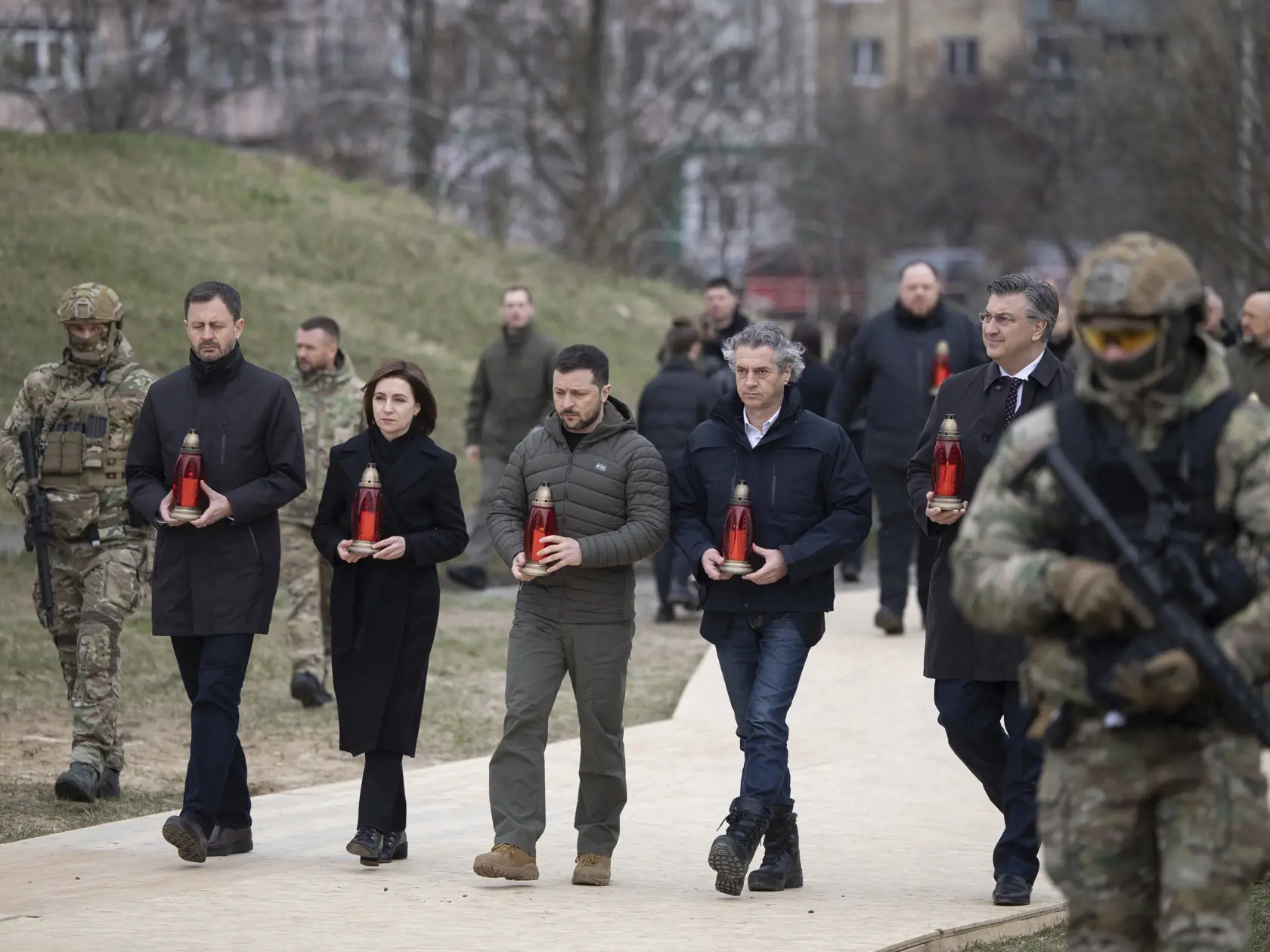 Na snímke zľava slovenský poremiír Eduard Heger, moldavská prezidentka Maia Sanduová, ukrajinský prezident Volodymyr Zelenskyj, slovinský premiér Robert Golob a chorvátsky premiér Andrej Plenkovič kráčajú so sviečkami počas pietnej ceremónie pri príležitosti výročia oslobodenia územia od ruských vojsk v ukrajinskom meste Buča v Kyjevskej oblasti v piatok 31. marca 2023.