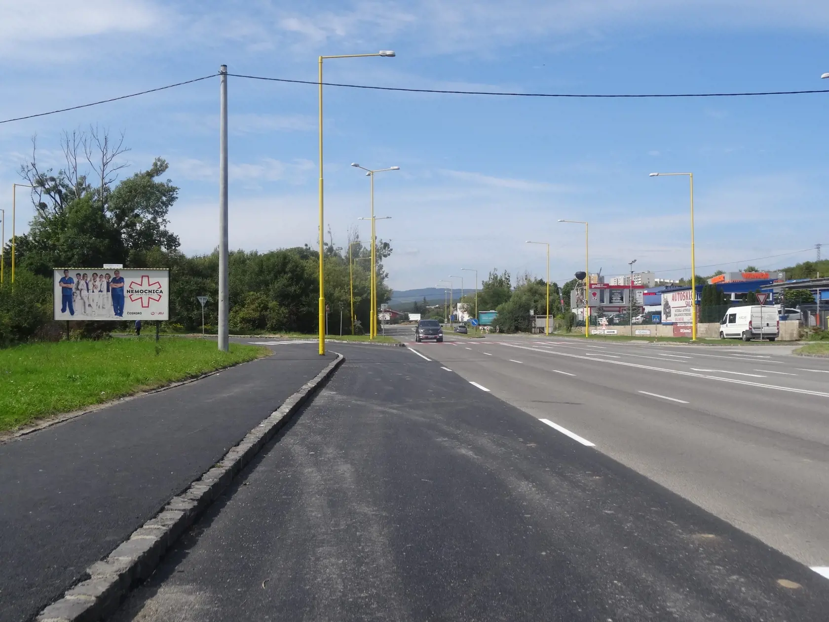 Hlavná cesta, ktorá vedie vedľa rómskeho sídliska. Je zrejmé, že jazdný pruh od sídliska, je čerstvo zrekonštruovaný.