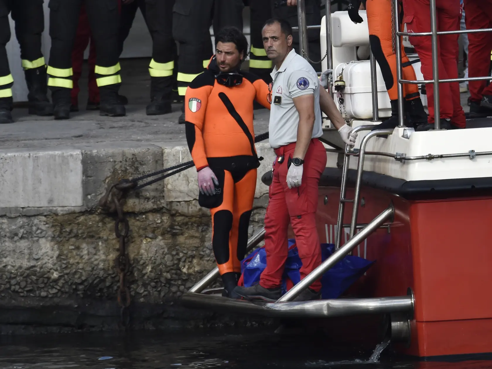 Talianski potápači vynášajú telo jednej z obetí potopenej plachetnice Bayesan.