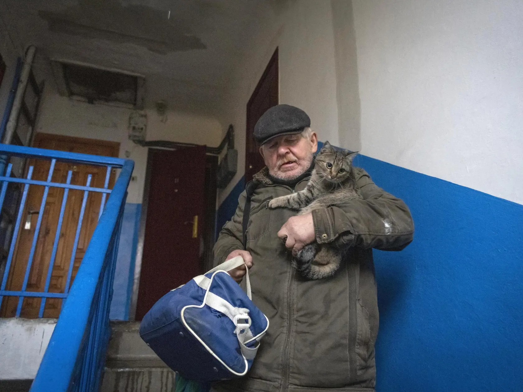 Miestny obyvateľ Leonid Tarasov drží v rukách mačku a tašku s osobnými vecami, keď odchádza zo svojho bytu v ukrajinskom meste Bachmut vo východoukrajinskej  Doneckej oblasti v stredu 26. októbra 2022.