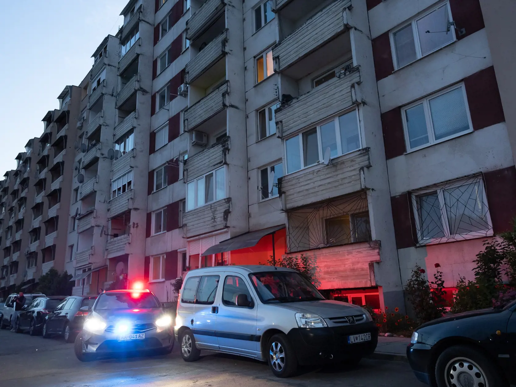 Na snímke sú policajti, ktorí berú na výsluch manželku atentátnika z ich bytu v Leviciach.