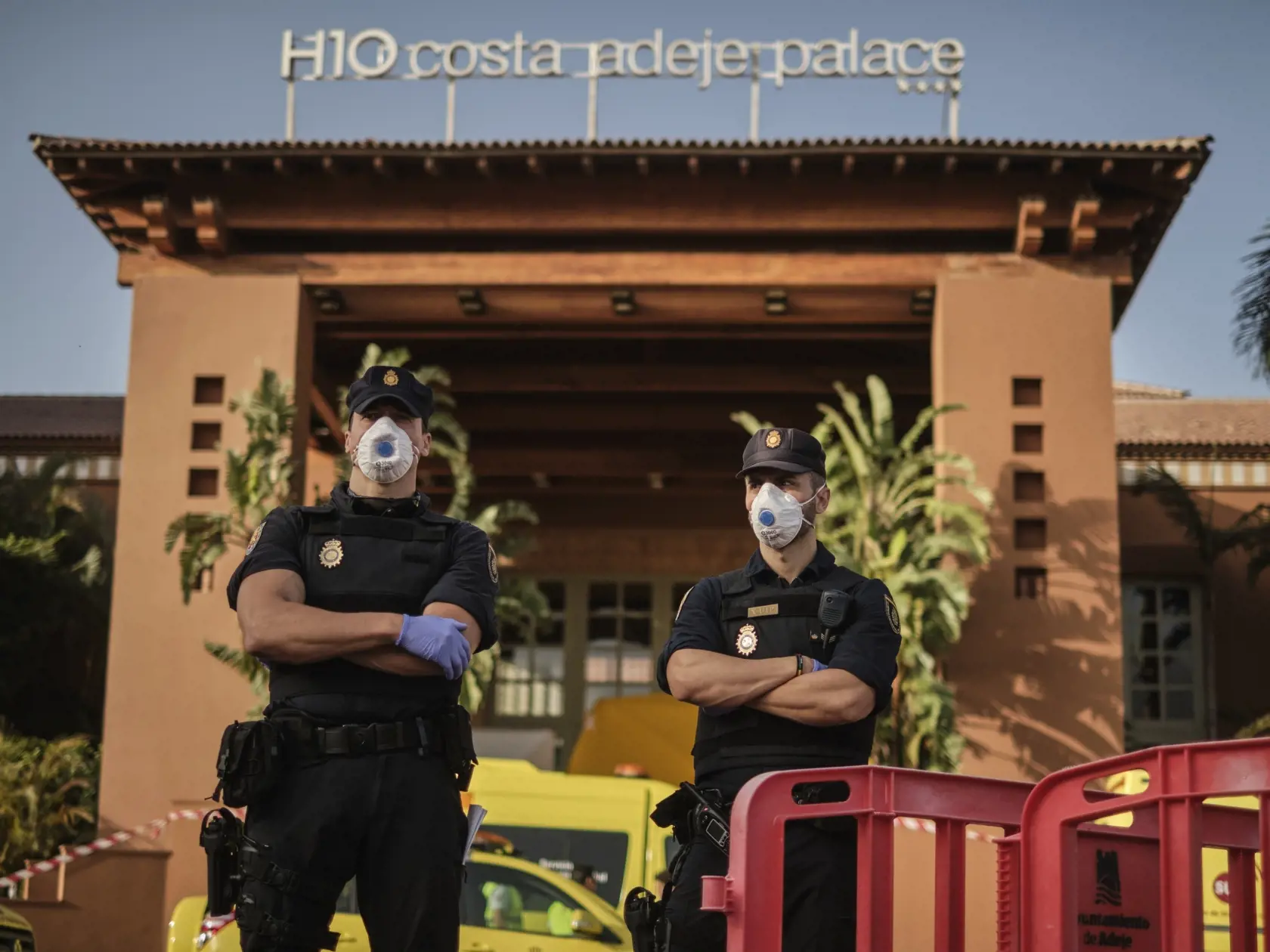 Na snímke policajti s ochrannými rúškami stoja pred hotelom H10 Costa Adeje Palace v meste La Caleta, na španielskom ostrove Tenerife 26. februára 2020.