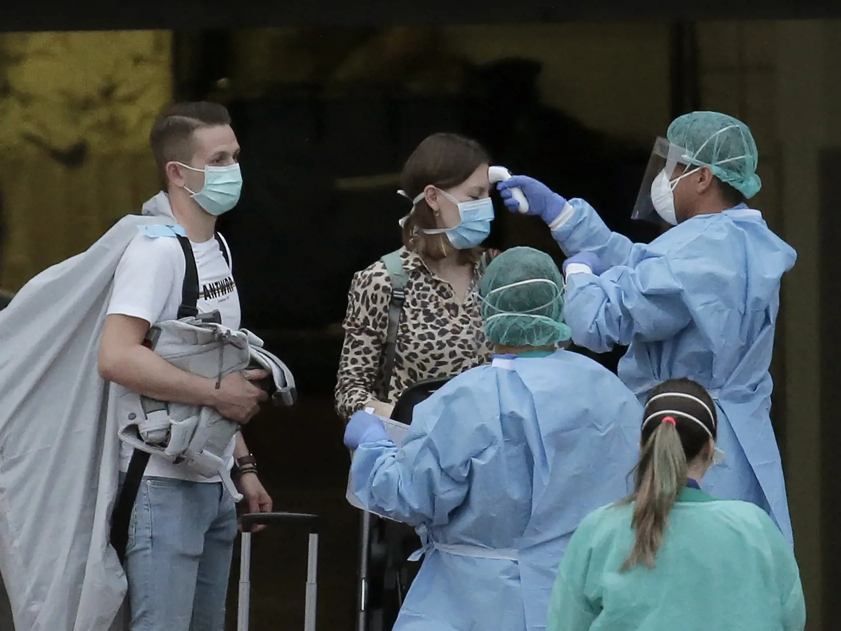 Zdravotný personál v ochranných odevoch meria teplotu turistke počas odchodu z Hotela H10 Costa Adeje Palace v letovisku Adeje na juhozápade španielskeho ostrova Tenerife v piatok 28. februára 2020.
