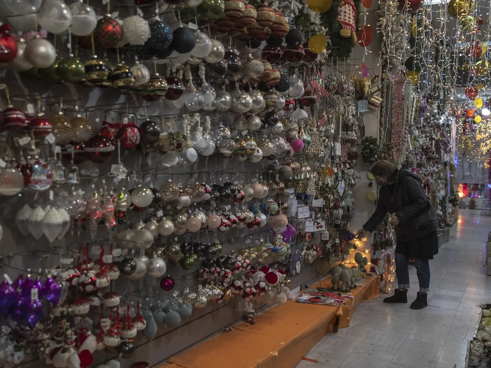 Zákaznička si prezerá vianočnú výzdobu v obchode v centre Atén.