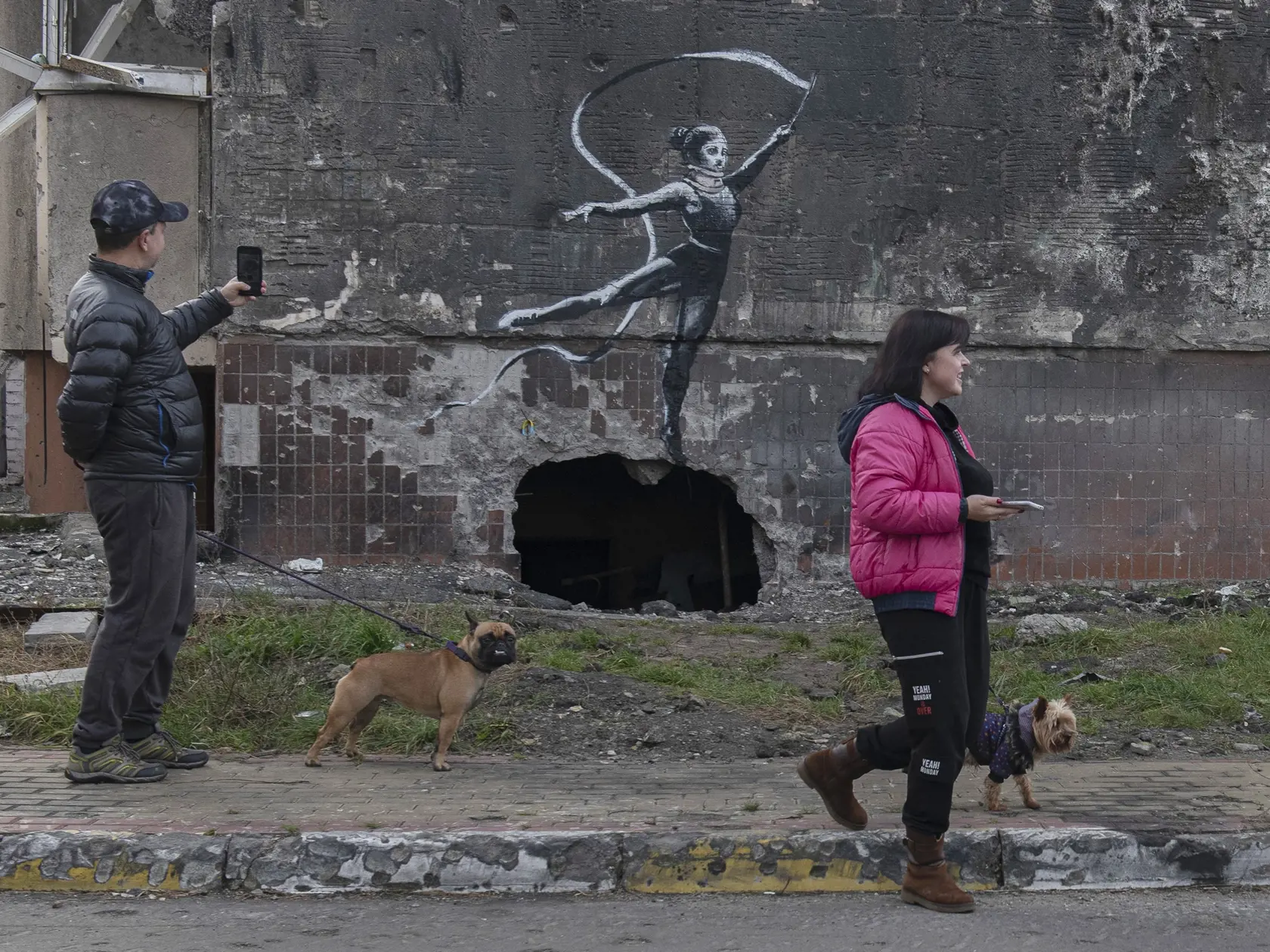 Na snímke dielo britského streetartového umelca Banksyho zobrazuje gymnastku s fixačným golierom na krku mávajúcu stuhou na budove poškodenej ostreľovaním 13. novembra 2022 v ukrajinskom meste Irpiň.