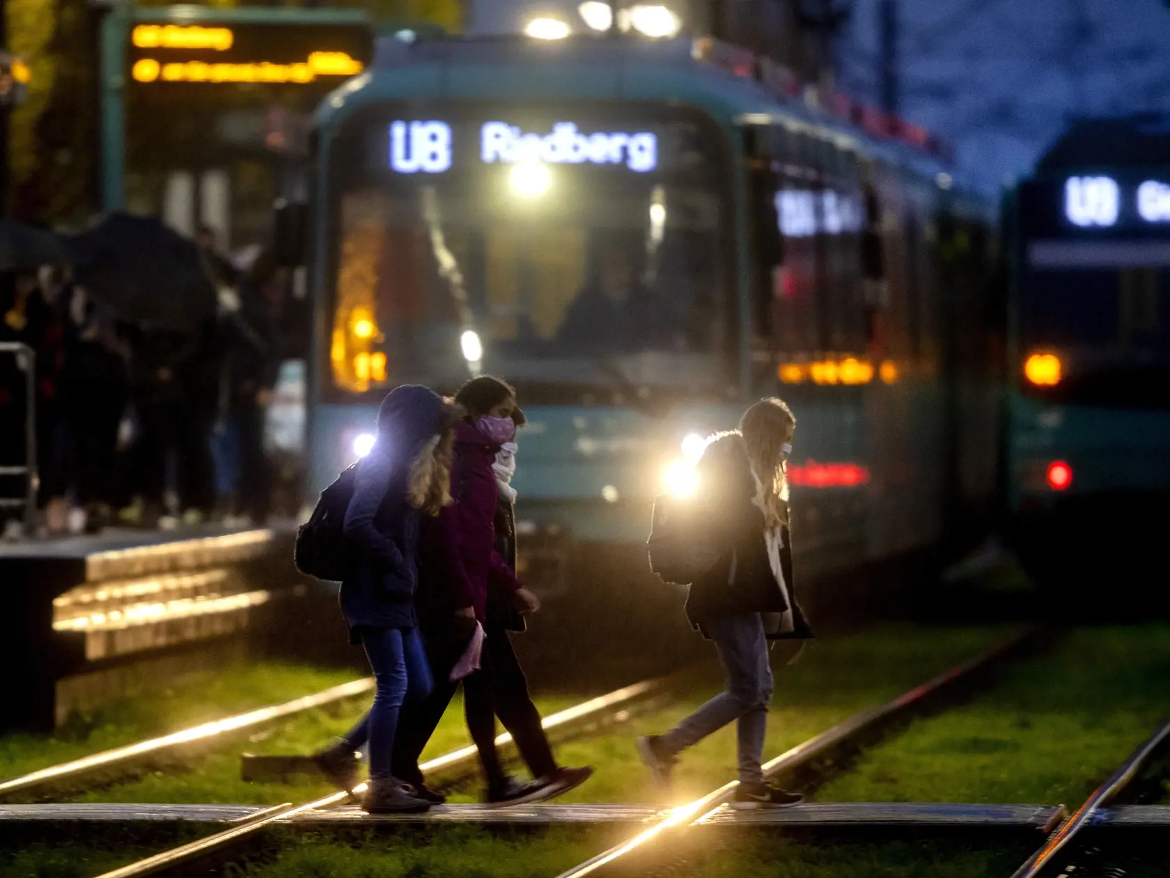 Školáci s ochrannými rúškami prechádzajú cez koľajnice na stanici metra vo Frankfurte nad Mohanom vo štvrtok 19. novembra 2020.