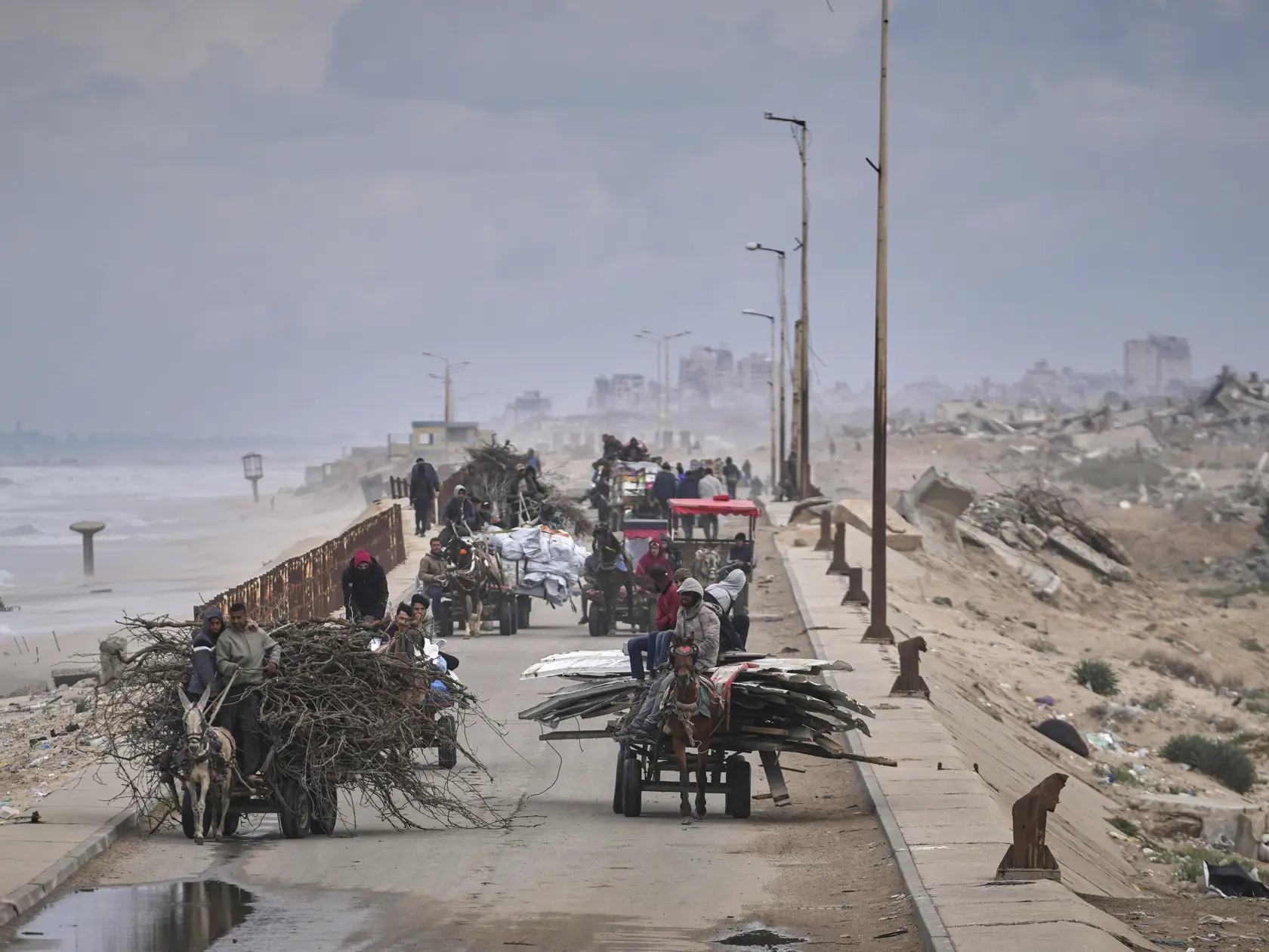 Vysídlení Palestínčania, ktorí nesú svoje veci, drevo a iné predmety, sa presúvajú medzi južnou a severnou časťou Gazy v meste Gaza 21- marca 2025. Izraelské opozičné strany a mimovládne organizácie ohlásili zámer napadnúť na najvyššom súde  rozhodnutie vlády, ktorá vo štvrtok z funkcie odvolala riaditeľa kontrarozviedky Šin Bet Ronena Bara.