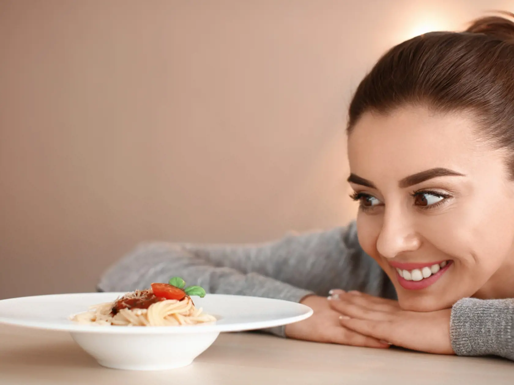 Young,Woman,Looking,At,Plate,With,Tasty,Pasta,On,Table