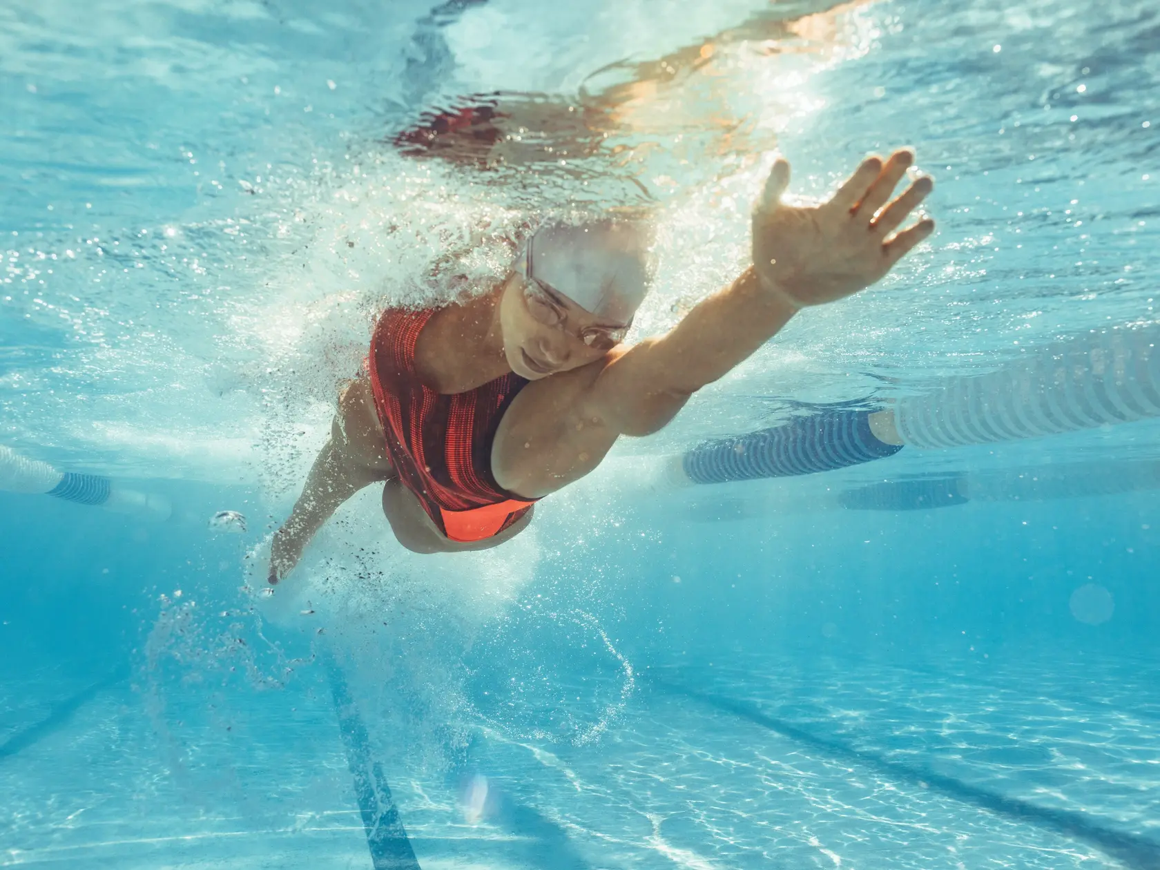 Underwater shot of female athlete swimming in pool. Young woman swimming the front crawl in a pool.