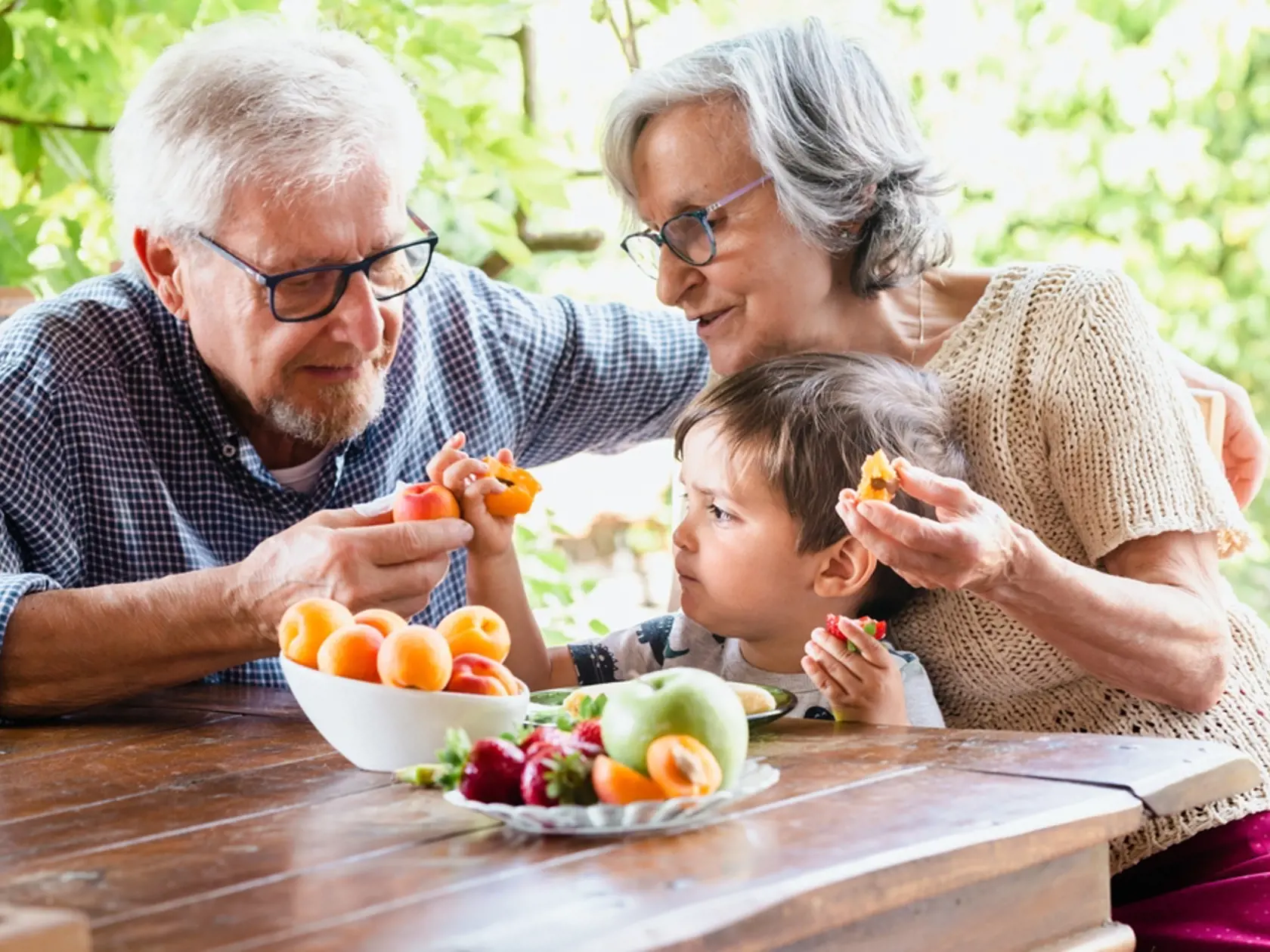 A,Young,Boy,Eating,Fruit,With,His,Grandparents,At,A