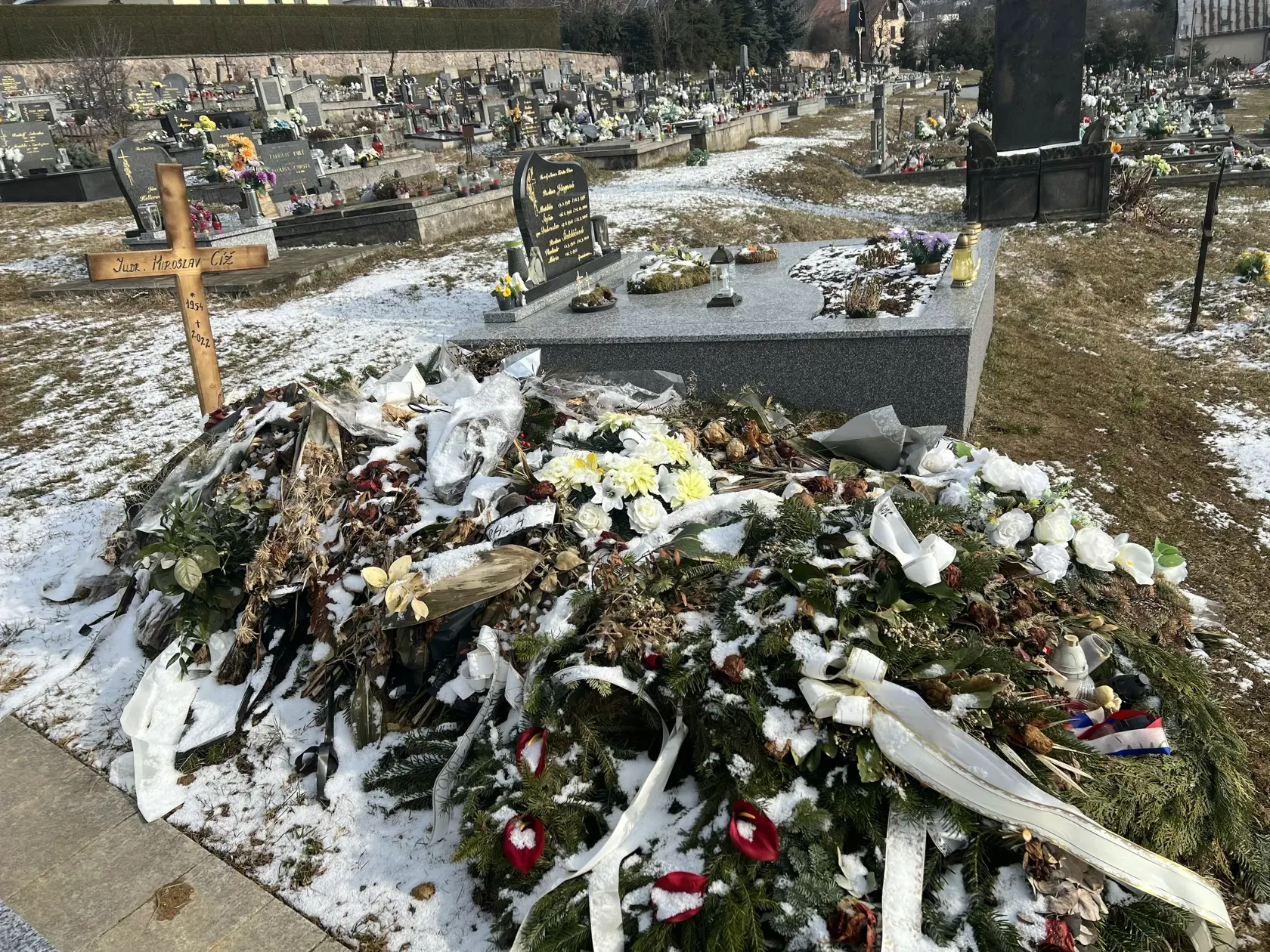 Namiesto pomníka tu dočasne stojí len jednoduchý drevený kríž a hrob pôsobí ako keby sa oň nik nestaral - ležia na ňom staré kvety ešte od pohrebu.