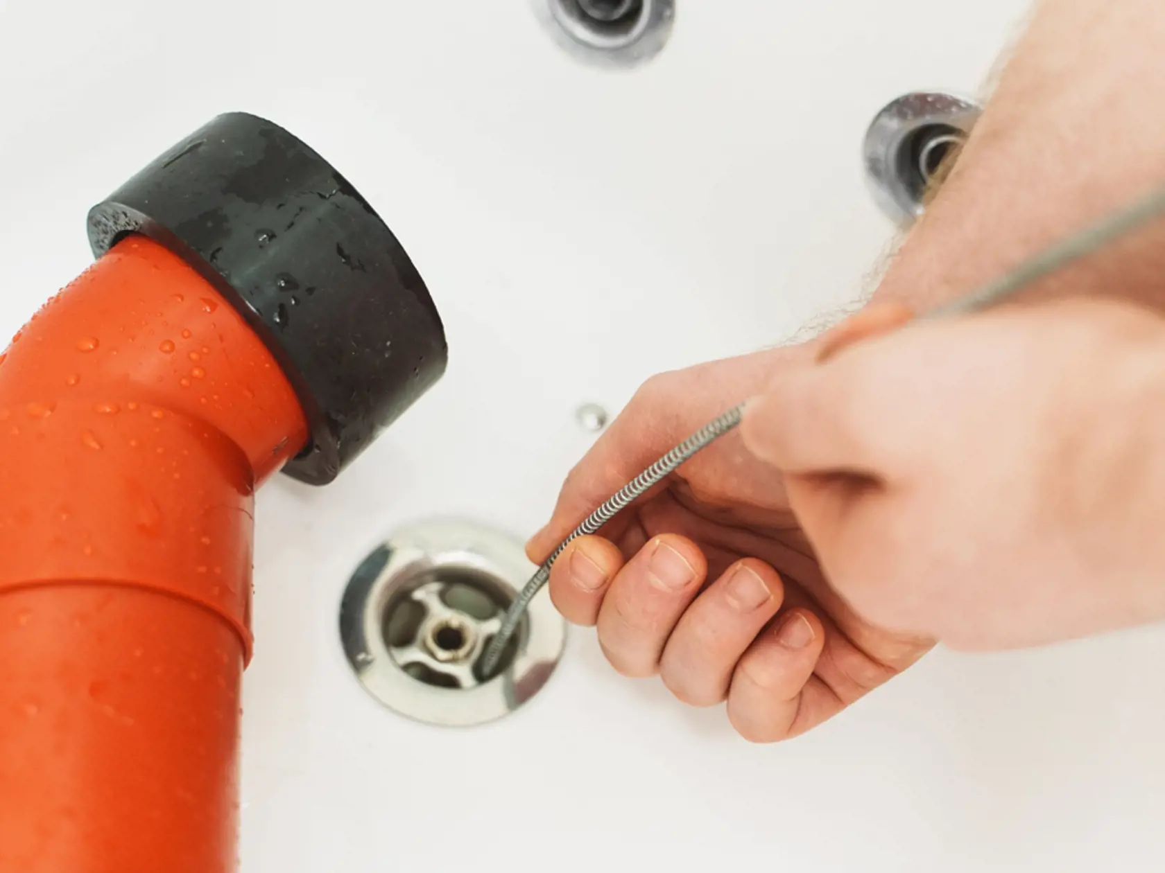 Plumber,Using,Drain,Snake,To,Unclog,Bathtub.