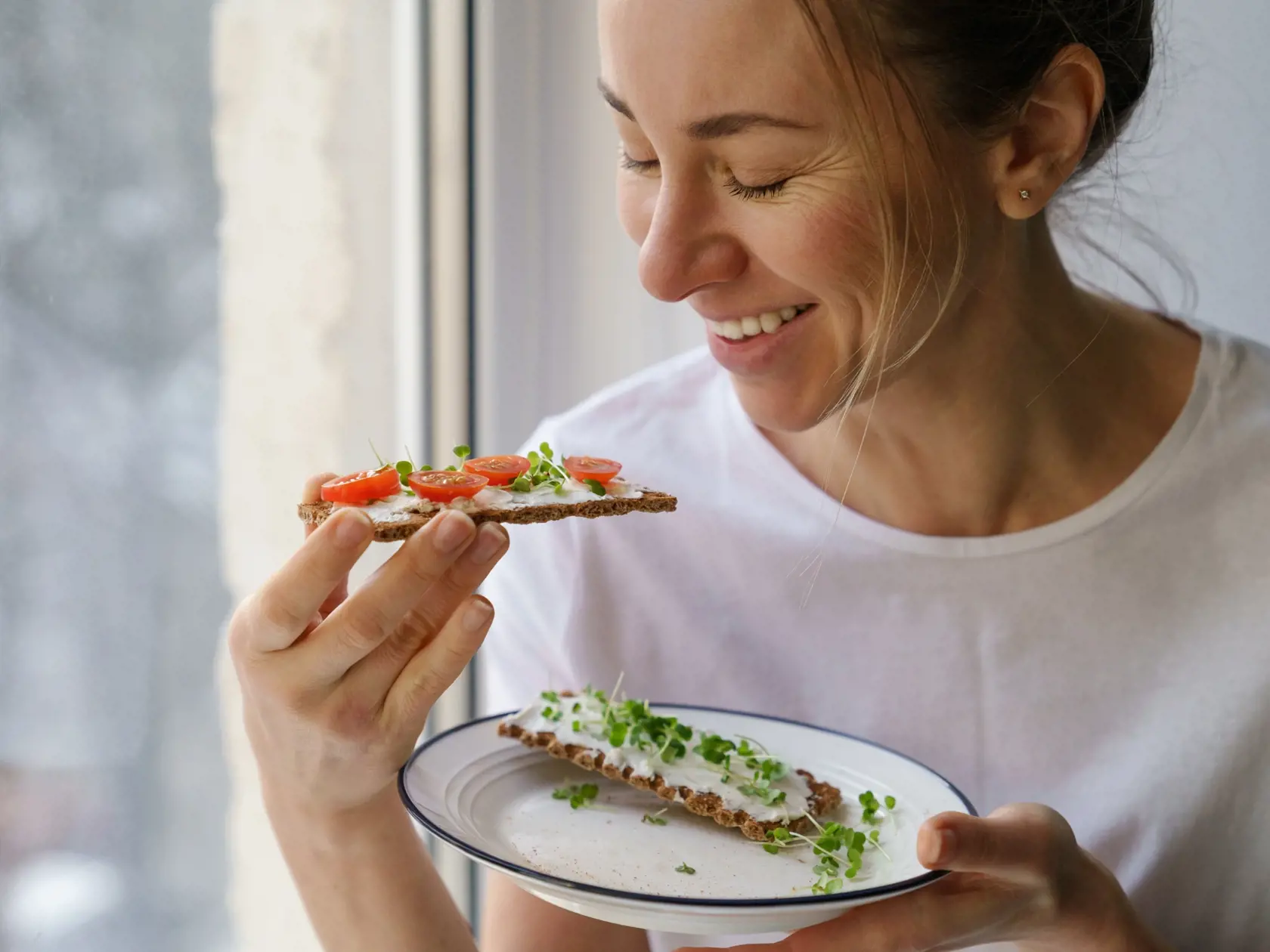Smiling,Woman,Eating,Rye,Crisp,Bread,With,Creamy,Vegetarian,Cheese