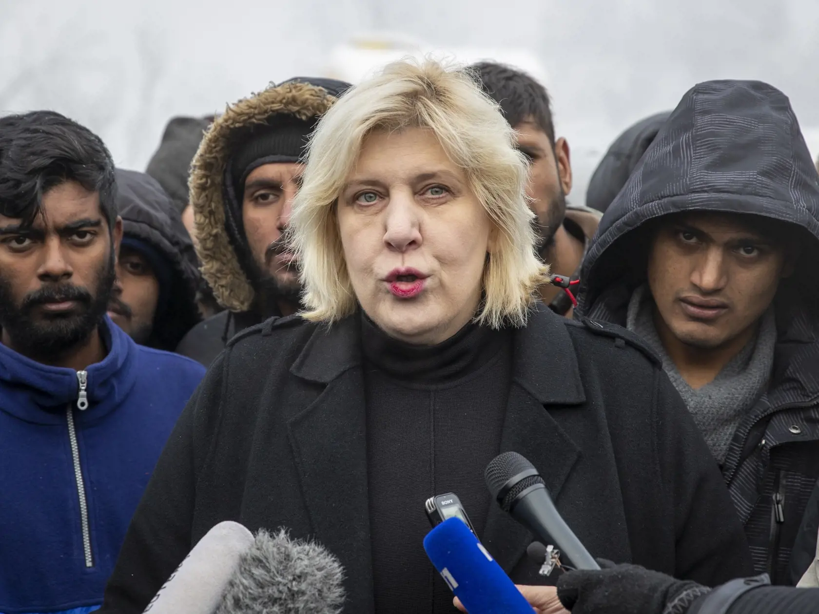 KK13 Bihač - Komisárka Rady Európy (RE) pre ľudské práva Dunja Mijatovičová obklopená migrantmi poskytuje rzhovor novinárom v dočasnom utečeneckom tábore Vučjak pri bosnianskom meste Bihač neďaleko hraníc s Chorvátskom 2. decembra 2019. Bosna a Hercegovina by mala bezodkladne zatvoriť dočasný utečenecký stanový tábor Vučjak ležiaci pri meste Bihač neďaleko hraníc s Chorvátskom. V opačnom prípade hrozí, že ľudia, ktorí tam žijú, cez zimu "začnú umierať". FOTO TASR/AP