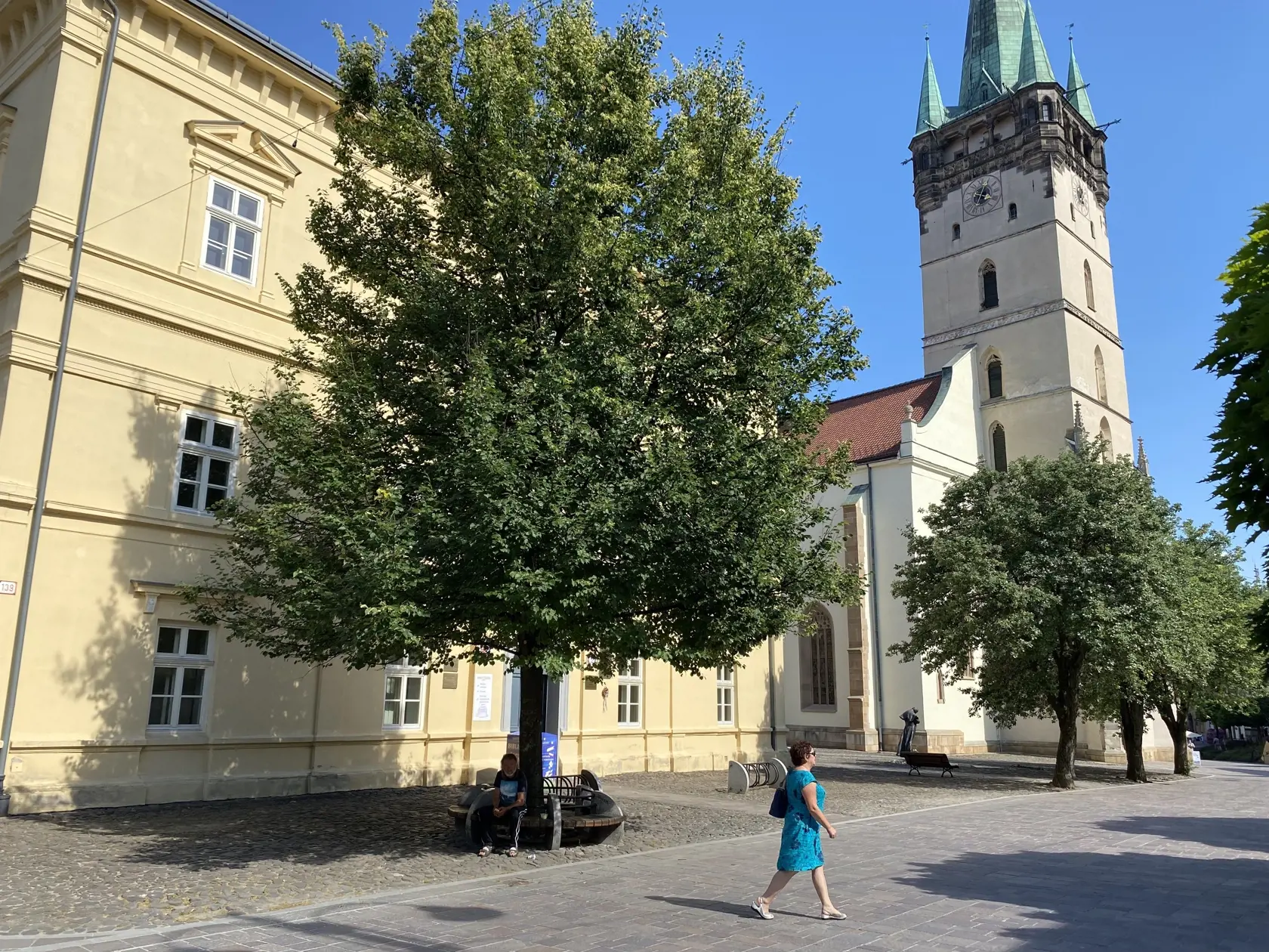 Centrum Prešova. Kamennú dlažbu medzi budovou knižnice patriacej Prešovskému samosprávnemu kraju a Konkatedrálou, pod tieňmi stromov , si vybral konzul na parkovanie svojho služobného auta.