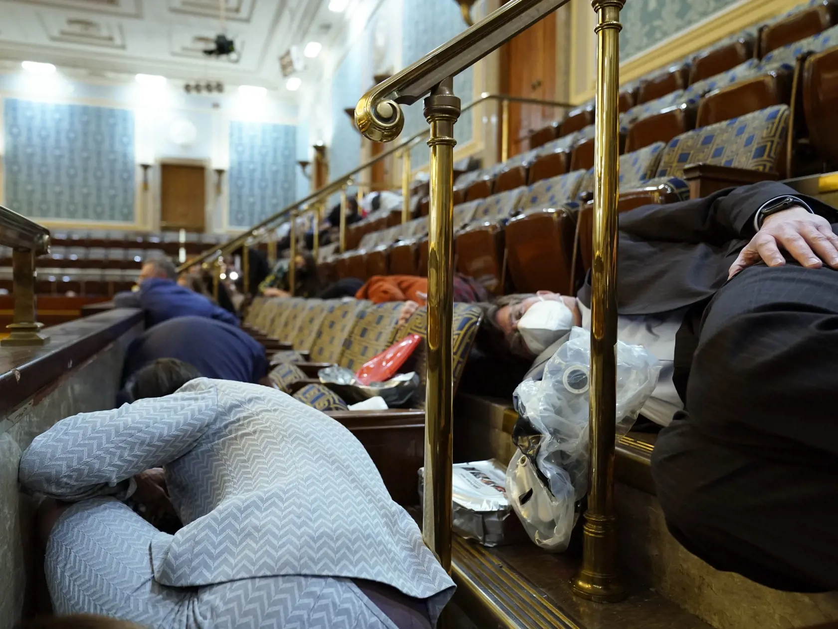 KK5 Washington - Na snímke ľudia sa ukrývajú po tom, čo protestujúci vtrhli do pléna Kongresu v americkom Kapitole vo Washingtone 6. januára 2021. Počas potýčok medzi protestujúcimi a policajtmi v sídle amerického Kongresu bola postrelená jedna osoba, ktorú previezli do nemocnice, informovala agentúra AP. Demonštranti podporujúci prezidenta Donalda Trumpa predtým prenikli do budovy Kapitolu a dostali sa aj do zasadacej sály Senátu, ukazujú zábery televízií C-Span a NBC. FOTO TASR/AP 

People she