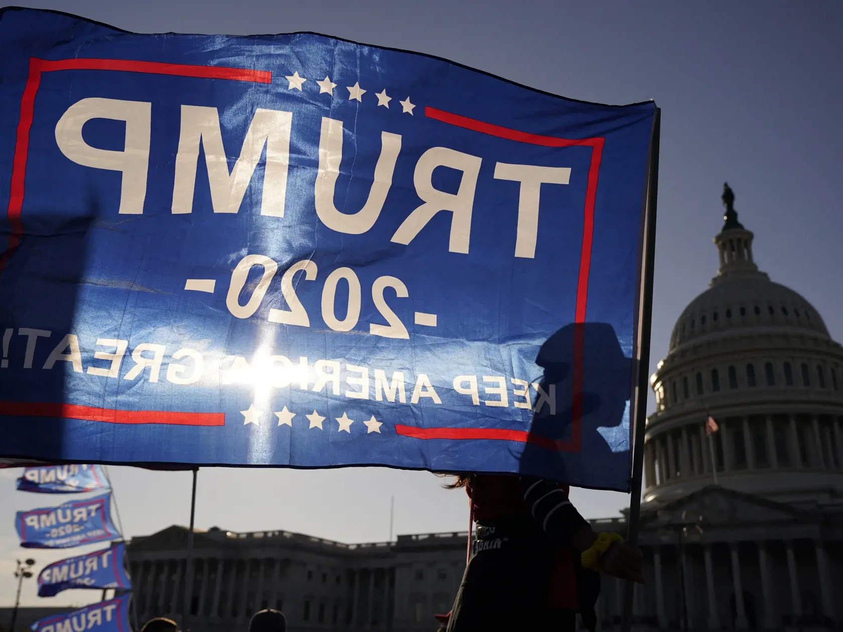 JB 7 Washington - Stúpenec amerického prezidenta Donalda Trumpa drží zástavu s nápisom Trump 2020 pred budovou amerického Kapitolu  počas protestného pochodu vo Washingtone 14. novembra 2020. Volebný tím amerického prezidenta Donalda Trumpa odvolal v nedeľu významnú časť svojej žaloby, ktorú podal v snahe zabrániť potvrdeniu výsledkov prezidentských volieb v štáte Pensylvánia. Prípad sa tak zúžil na menší počet hlasovacích lístkov, informovala agentúra Reuters. Pozmenená žaloba podaná na federál