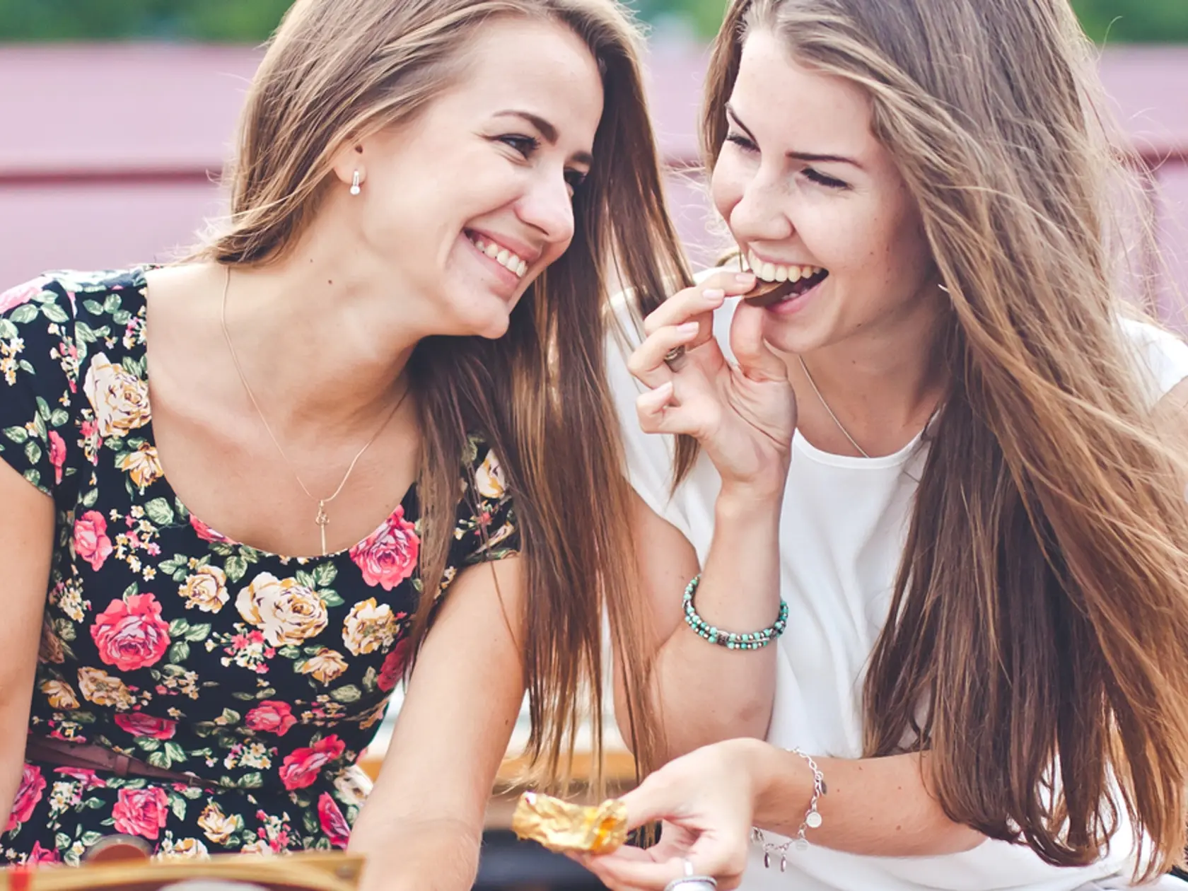 Two,Young,Female,Friends,Laugh,And,Eat,Chocolate,Outdoors
