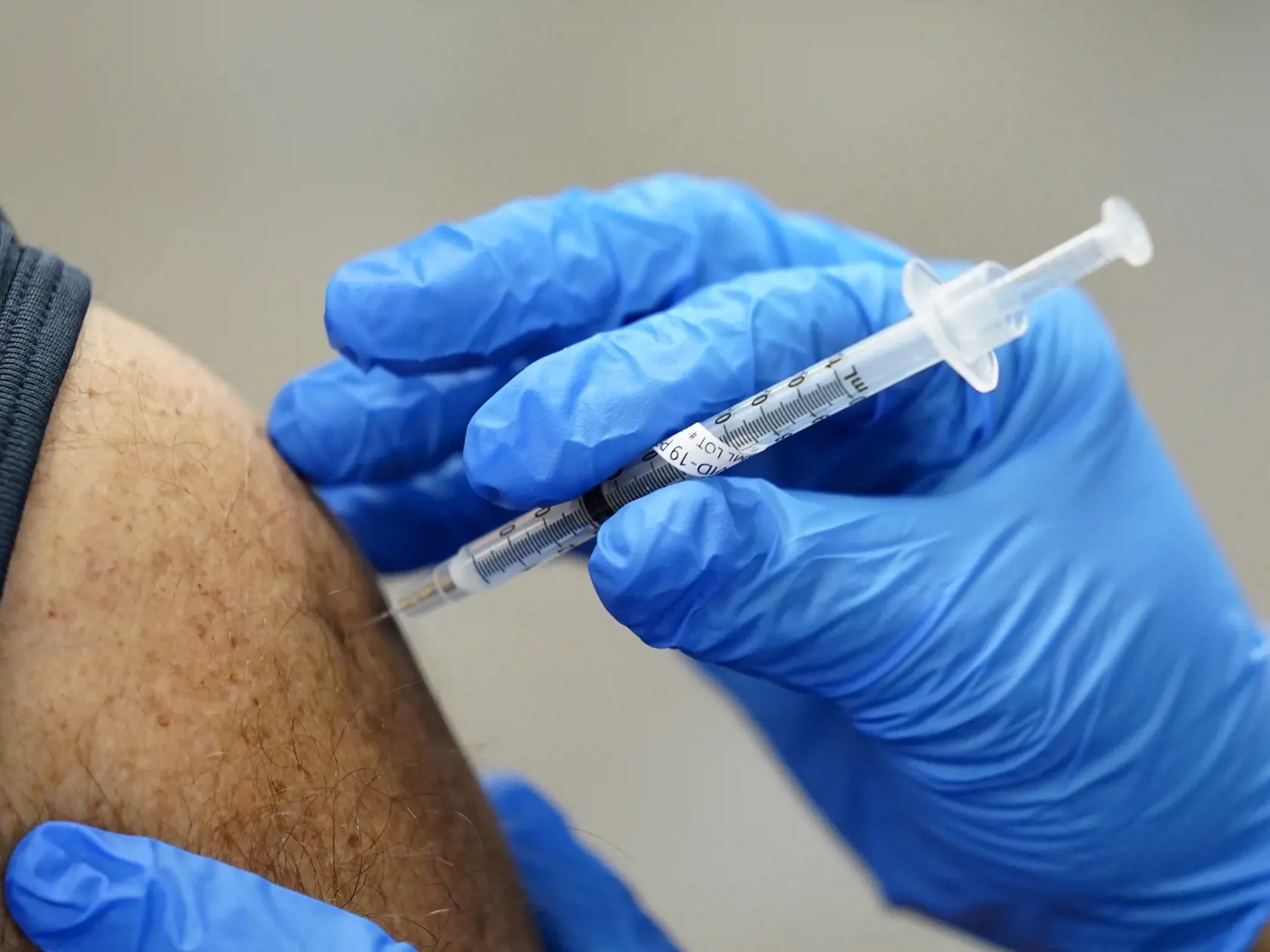 Zdravotník dostáva vakcínu proti koronavírusu od spoločnosti Pfizer-BioNTech počas očkovania.