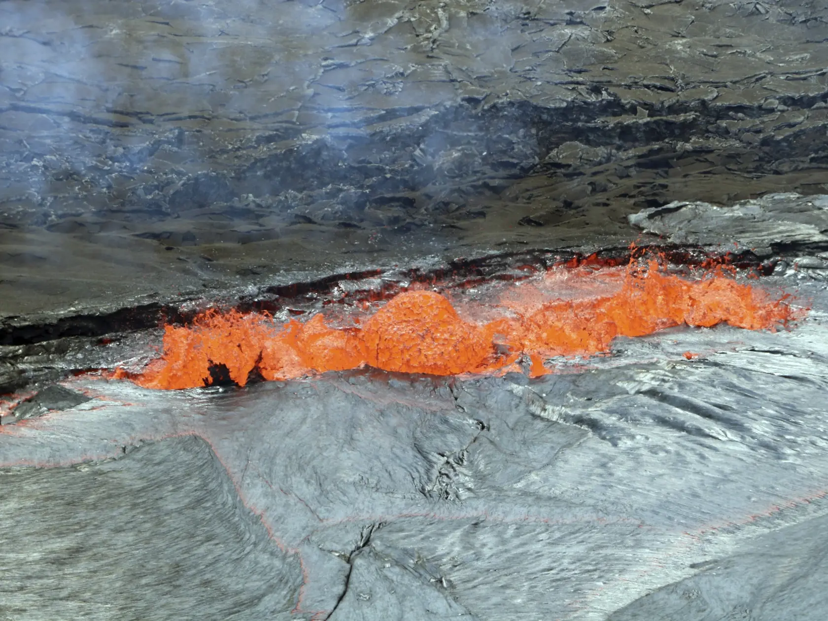 CORRECTS LOCATION TO HAWAII VOLCANOES NATIONAL PARK ON HAWAII'S BIG ISLAND - This April 22, 2018, photo provided by the U.S. Geological Survey shows a line of spattering along a lava lake margin with spatter being ejected well above the level of the Halema'uma'u Crater floor and occasional small bits landing on the rim with a piece of the thin, flexible crust on the lava lake being lifted and torn by a bubble burst at left in Kilauea Volcano in Hawaii Volcanoes National Park on Hawaii's Big Isla