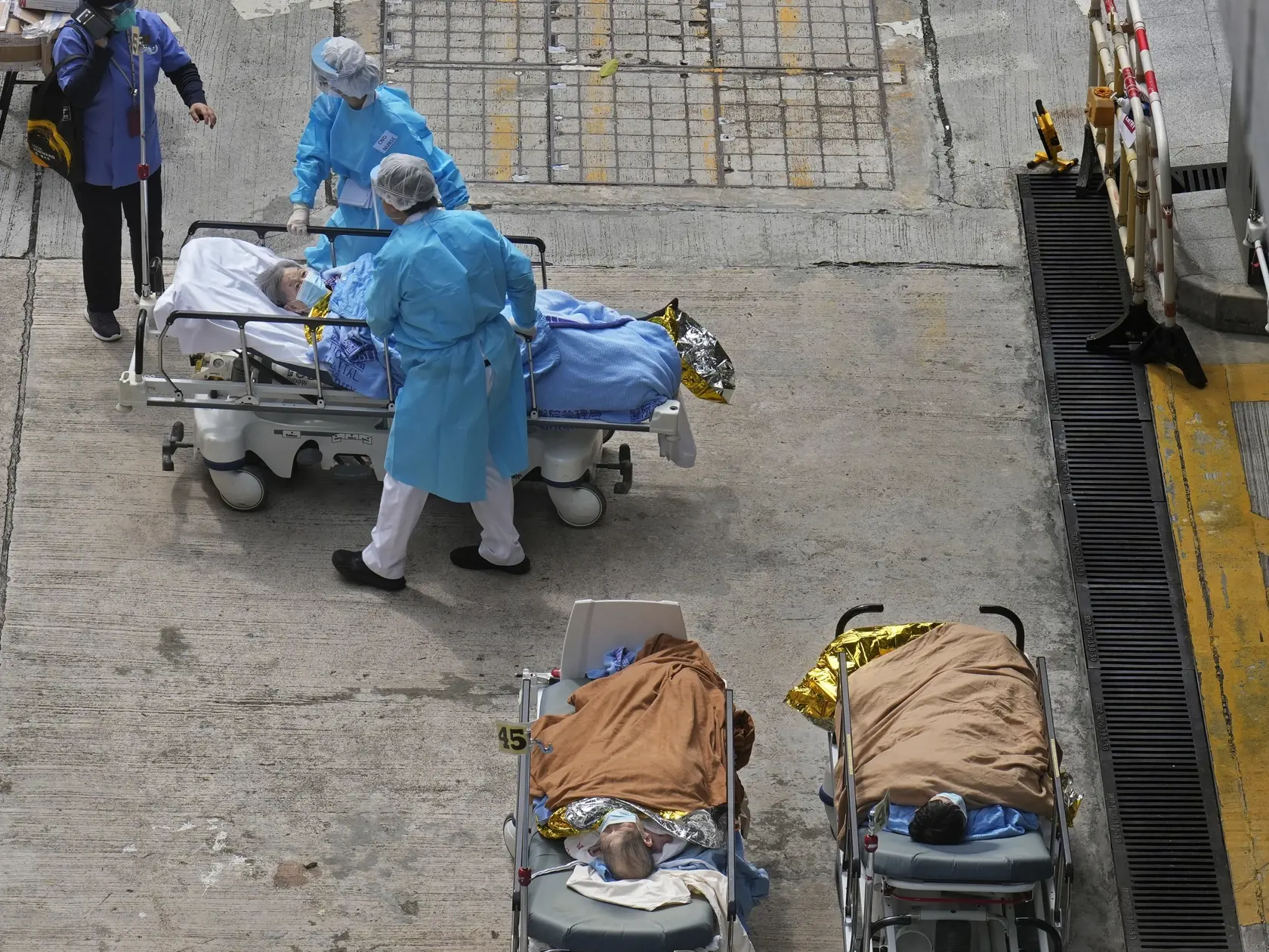 Pacienti ležia na nemocničných lôžkach a čakajú v provizórnych priestoroch pred zdravotníckym zariadením v Hongkongu 16. februára 2022.