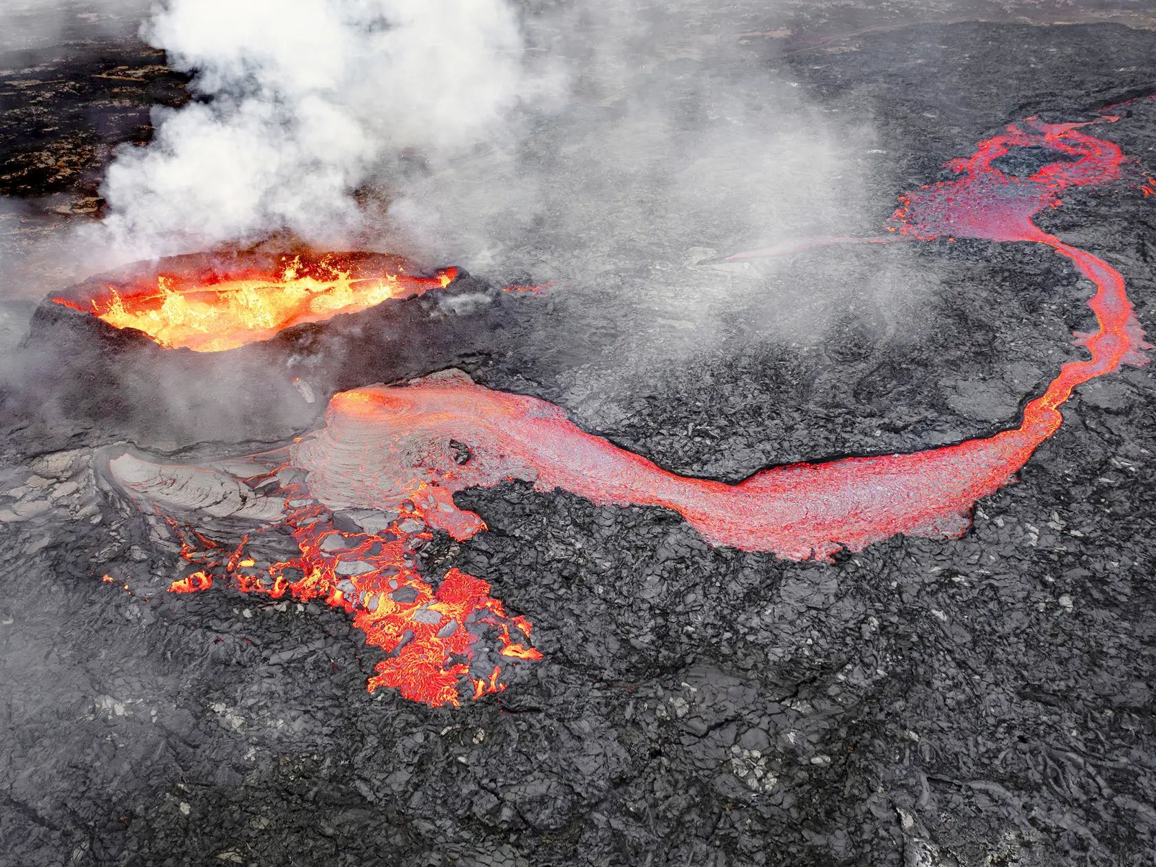 Horiaca sopka. Erupcia lávy prúdiacej cez okolie osvetľuje nočnú oblohu ohnivým spektrom farieb a vytvára dramatický a fascinujúci pohľad.