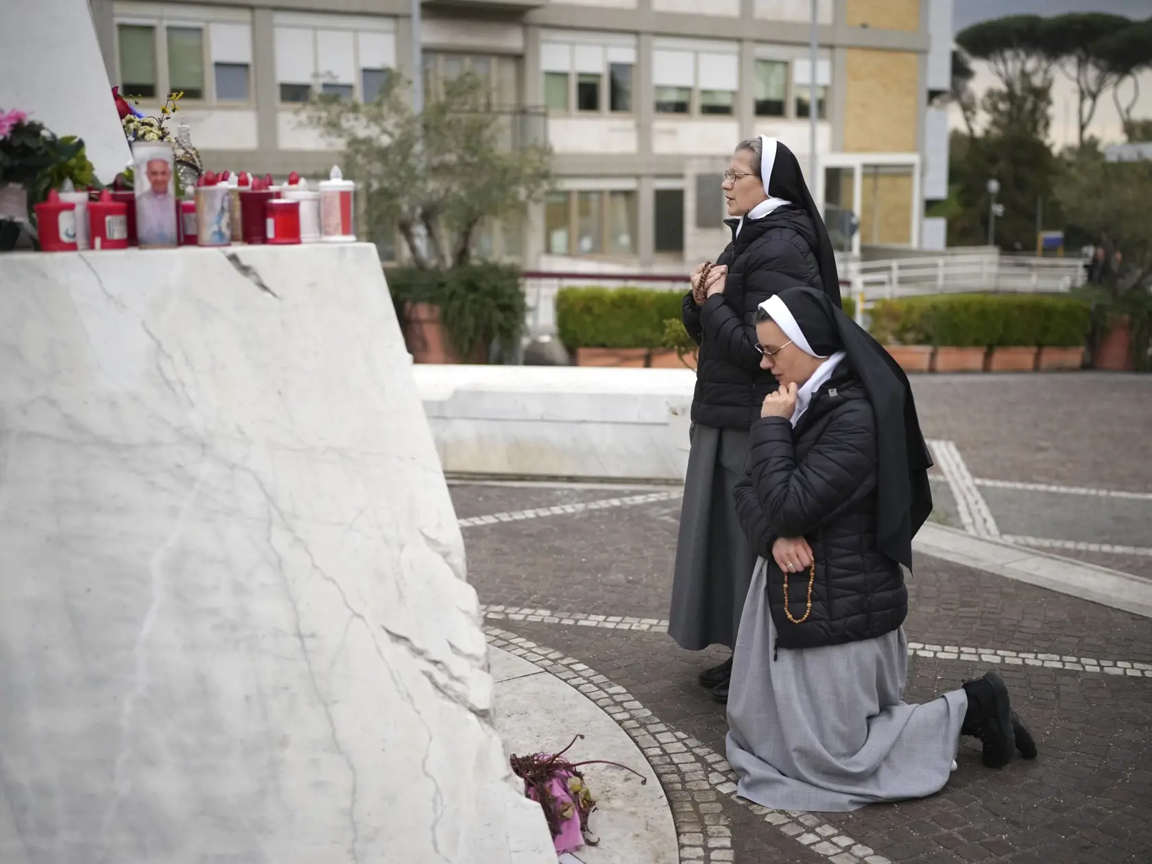 Mníšky sa modlia pred mramorovou sochou zosnulého pápeža Jána Pavla II. pred nemocnicou Agostino Gemelli v Ríme 20. februára 2025, kde je hospitalizovaný pápež František.