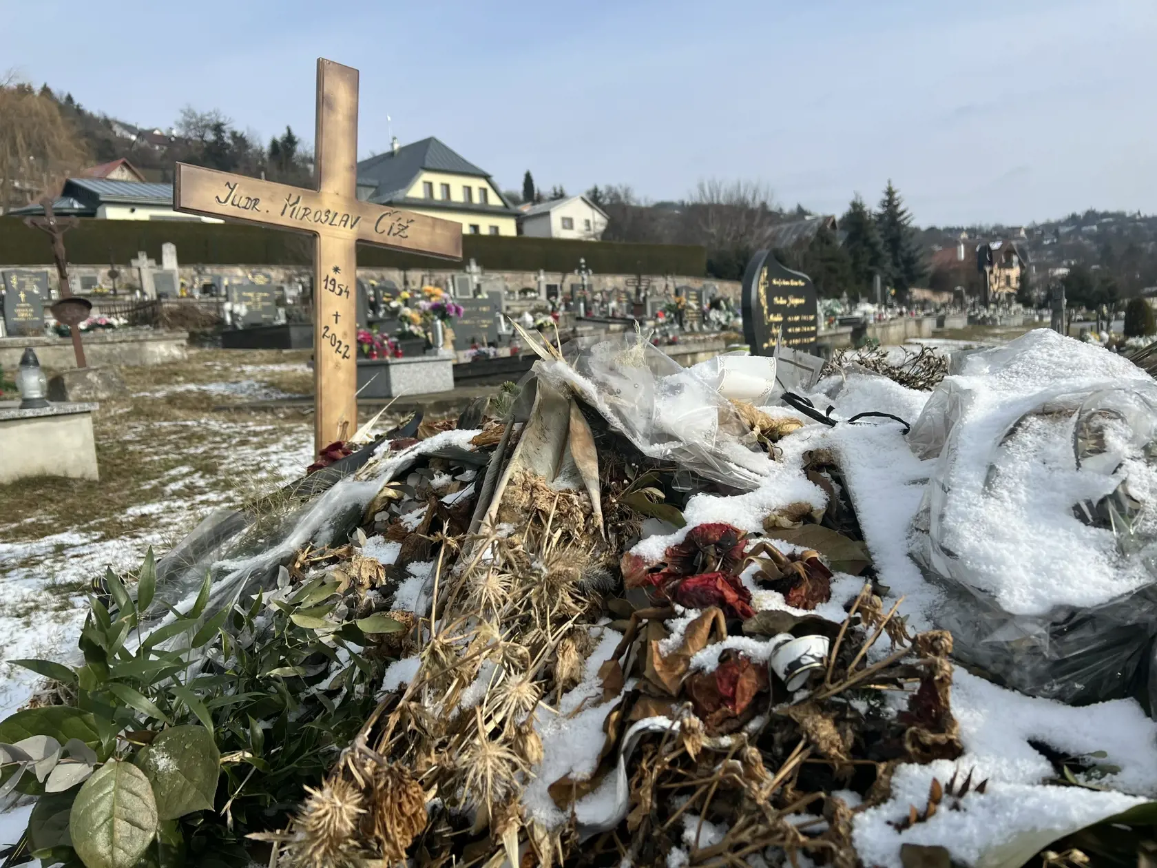 Namiesto pomníka tu dočasne stojí len jednoduchý drevený kríž a hrob pôsobí ako keby sa oň nik nestaral - ležia na ňom staré kvety ešte od pohrebu.