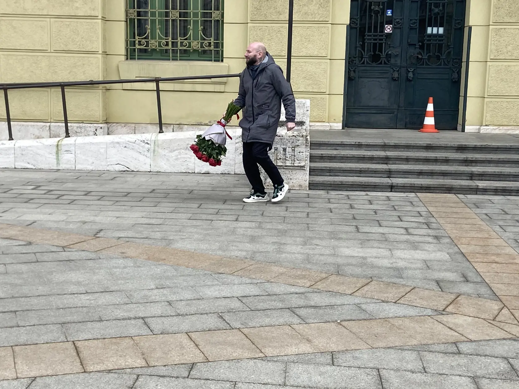 Kuriér. S kyticou sa vzdialil od dverí a telefonoval. Napokon prišla pani a prevzala si ju.