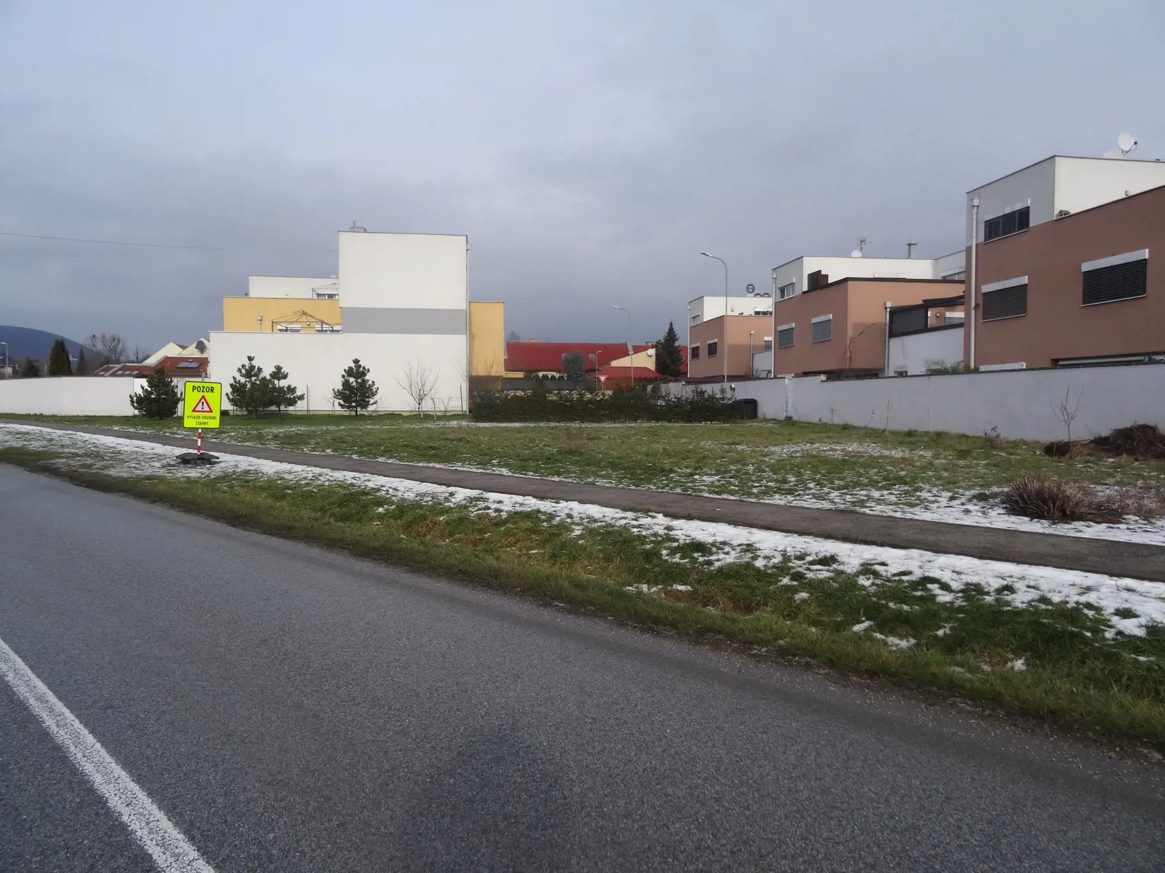 Radová zástavba stojí neďaleko frekventovanej cesty.
