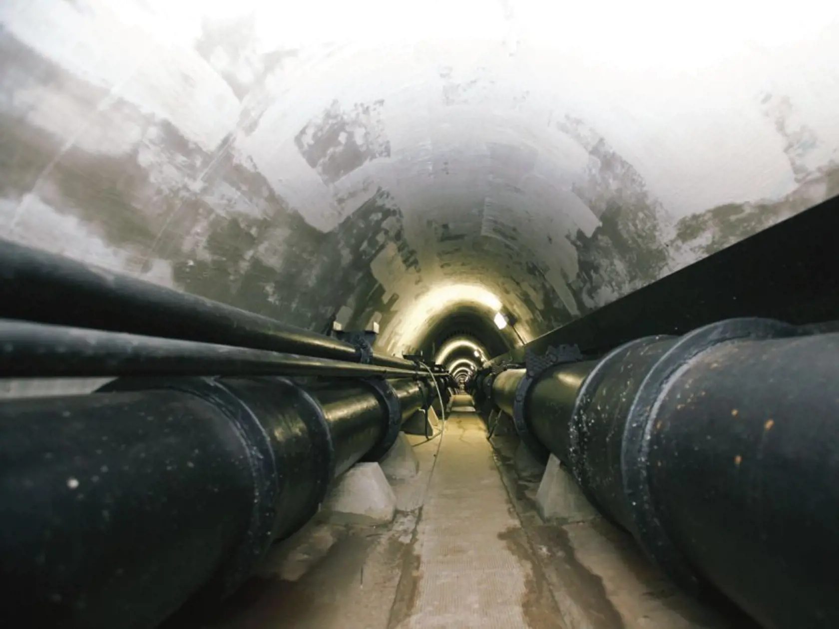 Tunel s potrubím vedie popod rameno, vyúsťuje