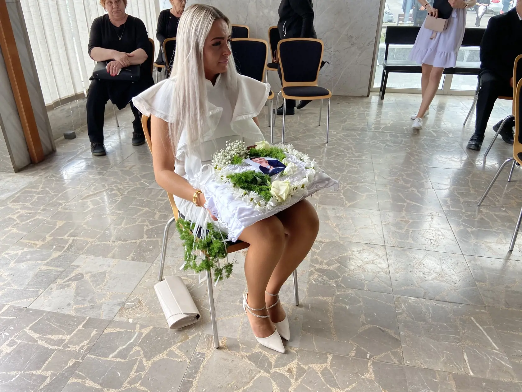 Žena v bielom s vankúšikom s pierkami predstavovala nevestu.