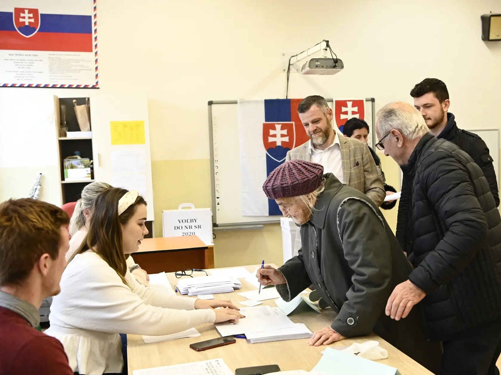 Na snímke 103-ročná volička Gizela Dvončová si preberá hlasovacie lístky od členov okrskovej volebnej komisie vo voľbách do Národnej rady SR vo volebnej miestnosti v Partizánskom 29. februára 2020. FOTO TASR - Radovan Stoklasa