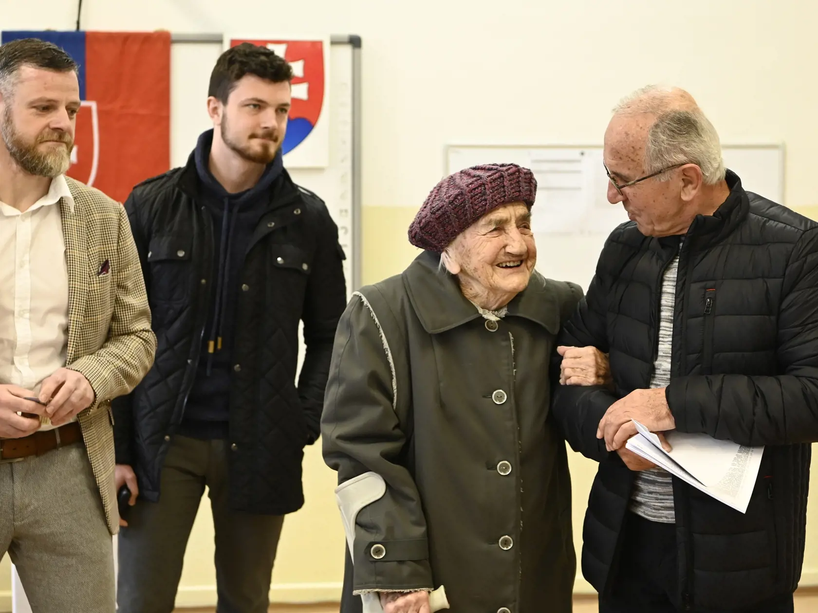 Na snímke druhá zľava 103-ročná volička Gizela Dvončová čaká vo volebnej miestnosti spolu s 75-ročným synom Ľubomírom (vpravo), 43-ročným vnukom Jurajom (vľavo) a 21-ročným pravnukom Michalom (druhý zľava) vo voľbách do Národnej rady SR v Partizánskom 29. februára 2020. FOTO TASR - Radovan Stoklasa