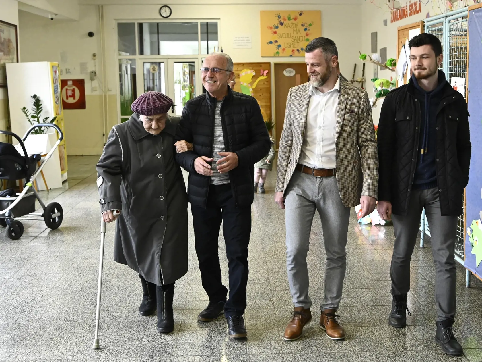 Na snímke zľava 103-ročná volička Gizela Dvončová prichádza do volebnej miestnosti spolu s 75-ročným synom Ľubomírom, 43-ročným vnukom Jurajom a 21-ročným pravnukom Michalom vo voľbách do Národnej rady SR v Partizánskom 29. februára 2020. FOTO TASR - Radovan Stoklasa