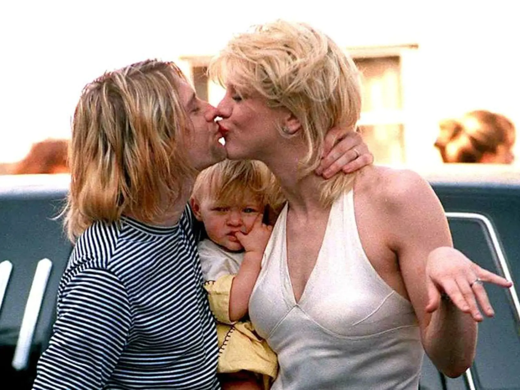 Kurt Cobain bozkáva svoju manželku Courtney Love na snímke z apríla 1994.