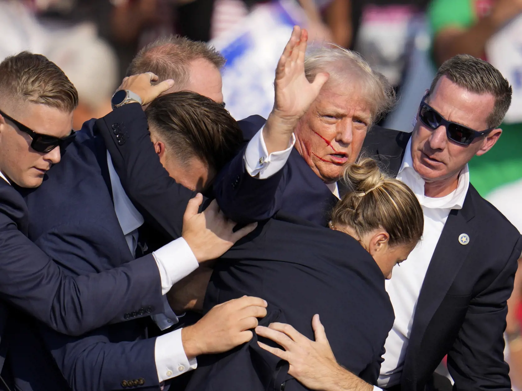Republikánsky prezidentský kandidát Donald Trump (druhý sprava) máva pri odchode z pódia za pomoci ochrankárov z predvolebného mítingu v meste Butler v americkom štáte Pensylvánia 13. júla 2024. Trump potvrdil, že v sobotu na mítingu v Pensylvánii ho zasiahla guľka. Tá mu prestrelila hornú časť pravého ucha. Bývalý americký prezident sa vyjadril na sociálnej sieti, informuje TASR.